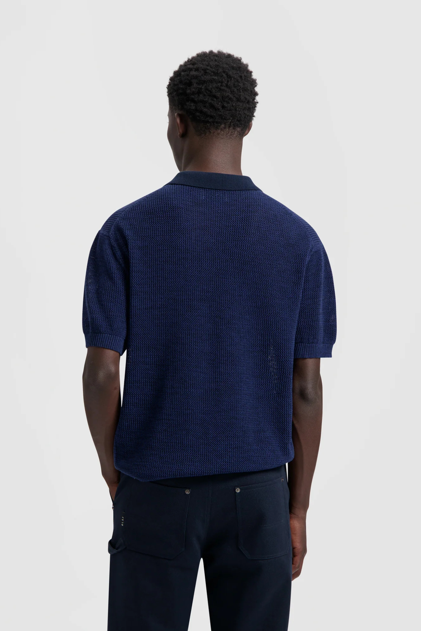 Model wearing the Olaf polo knit in dark navy. Back view