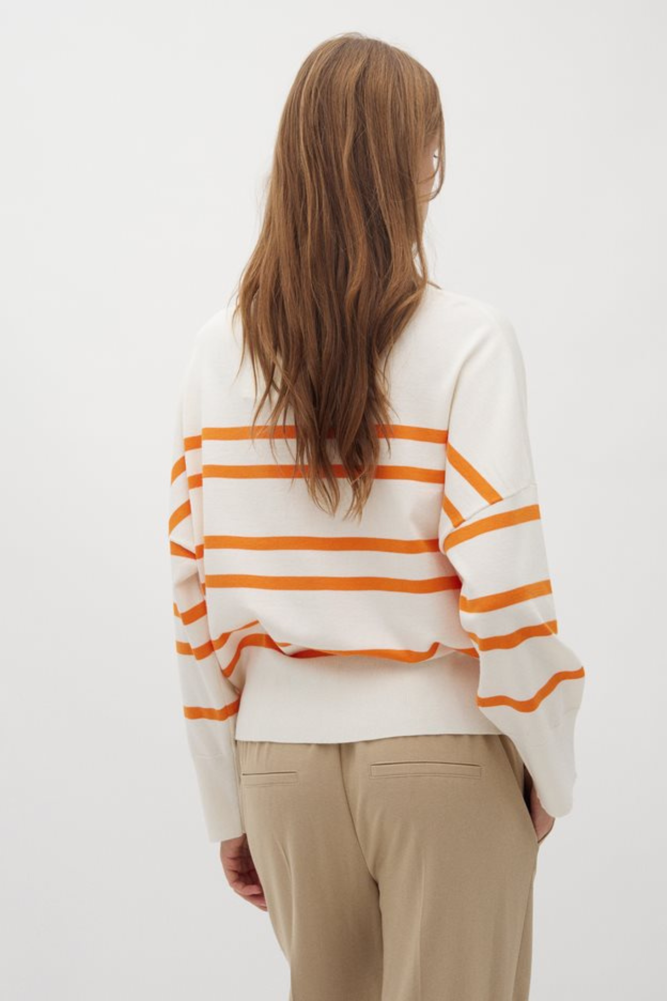 Model wearing the Mbym gillian bravana knit in white and orange. Back view