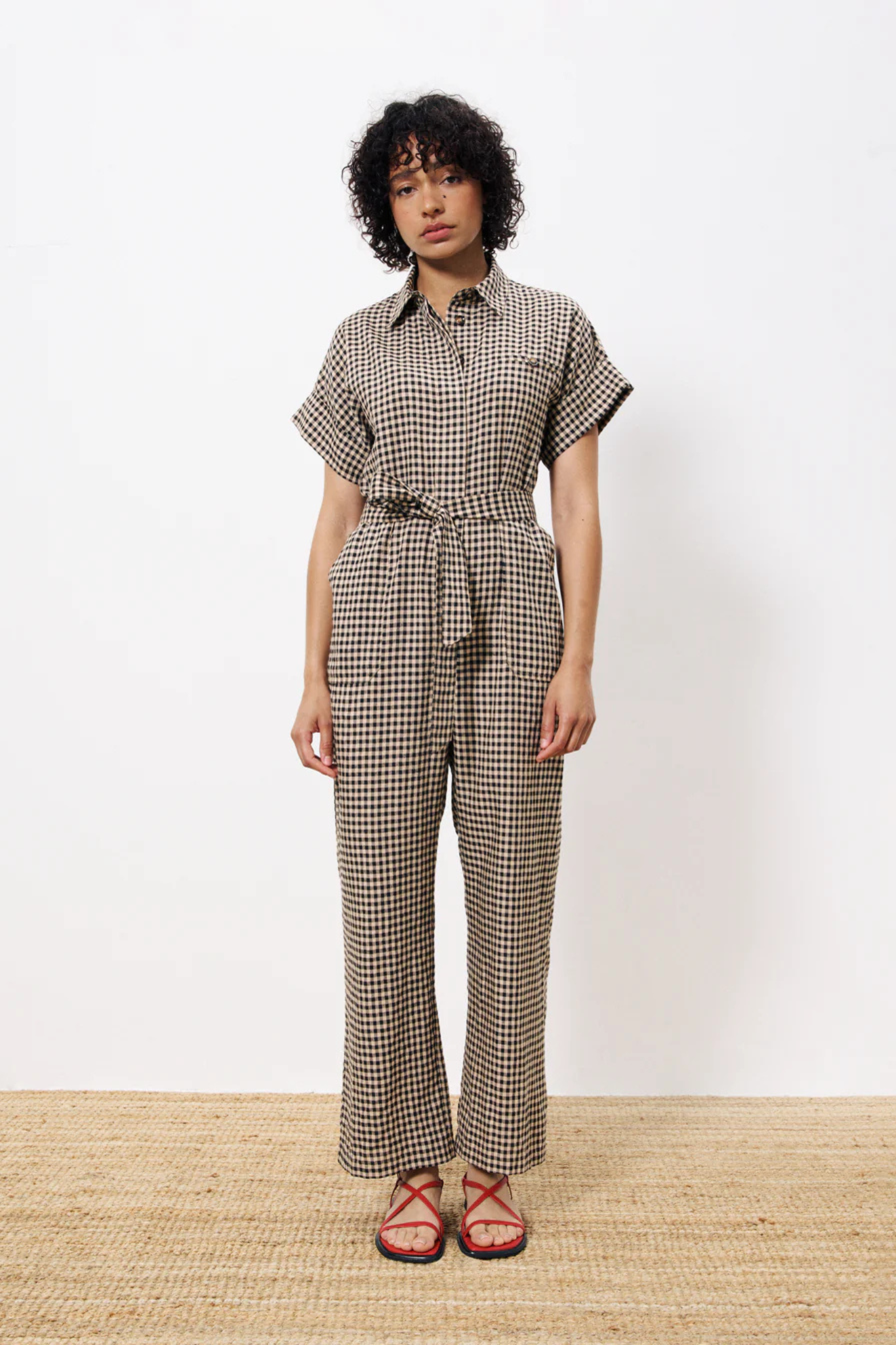 Model wearing the FRNCH elfie jumpsuit in black and beige checked. Front view