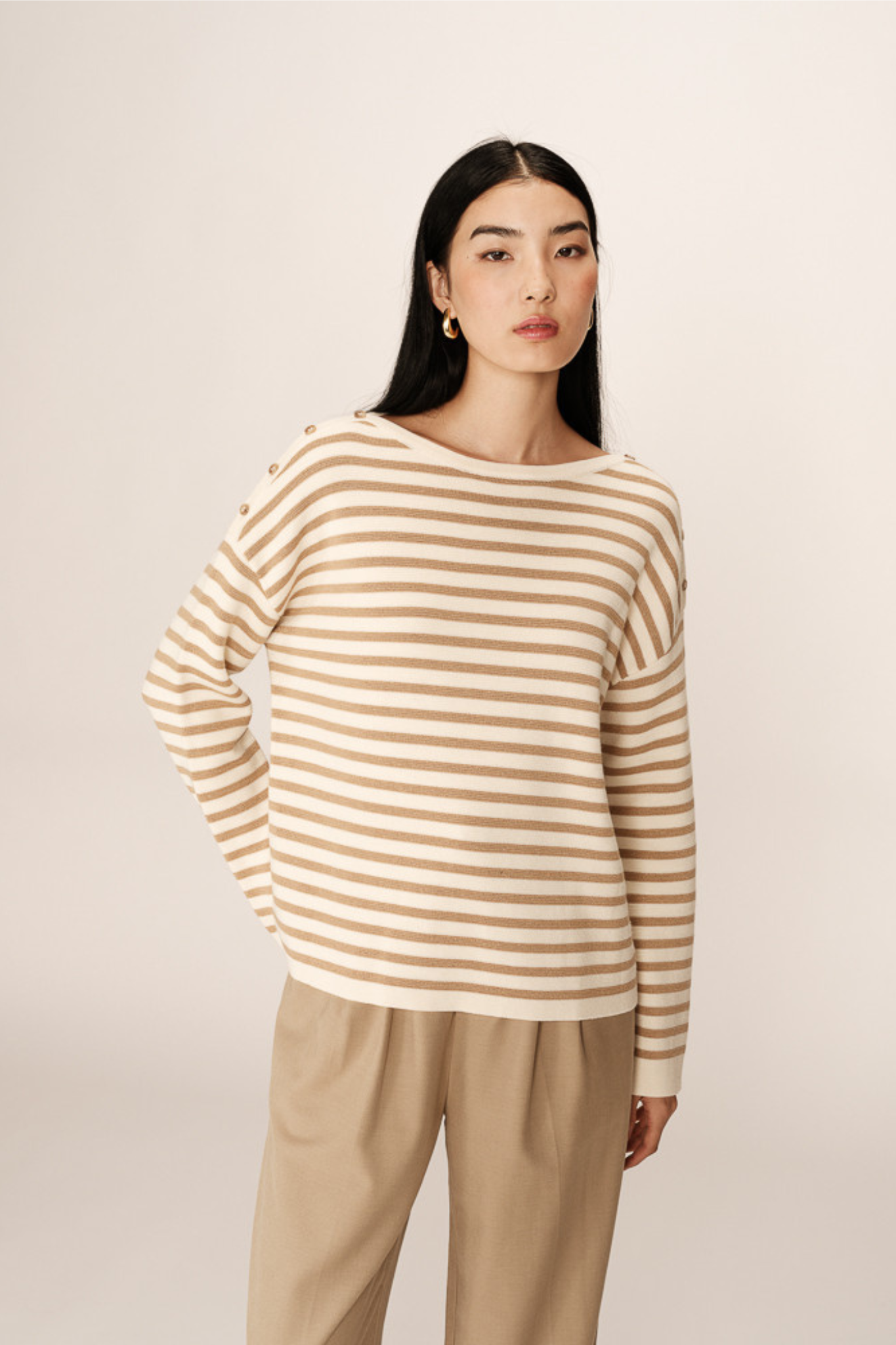 Model wearing the Grace & Mila pachamama sweater in gold and beige. Front view