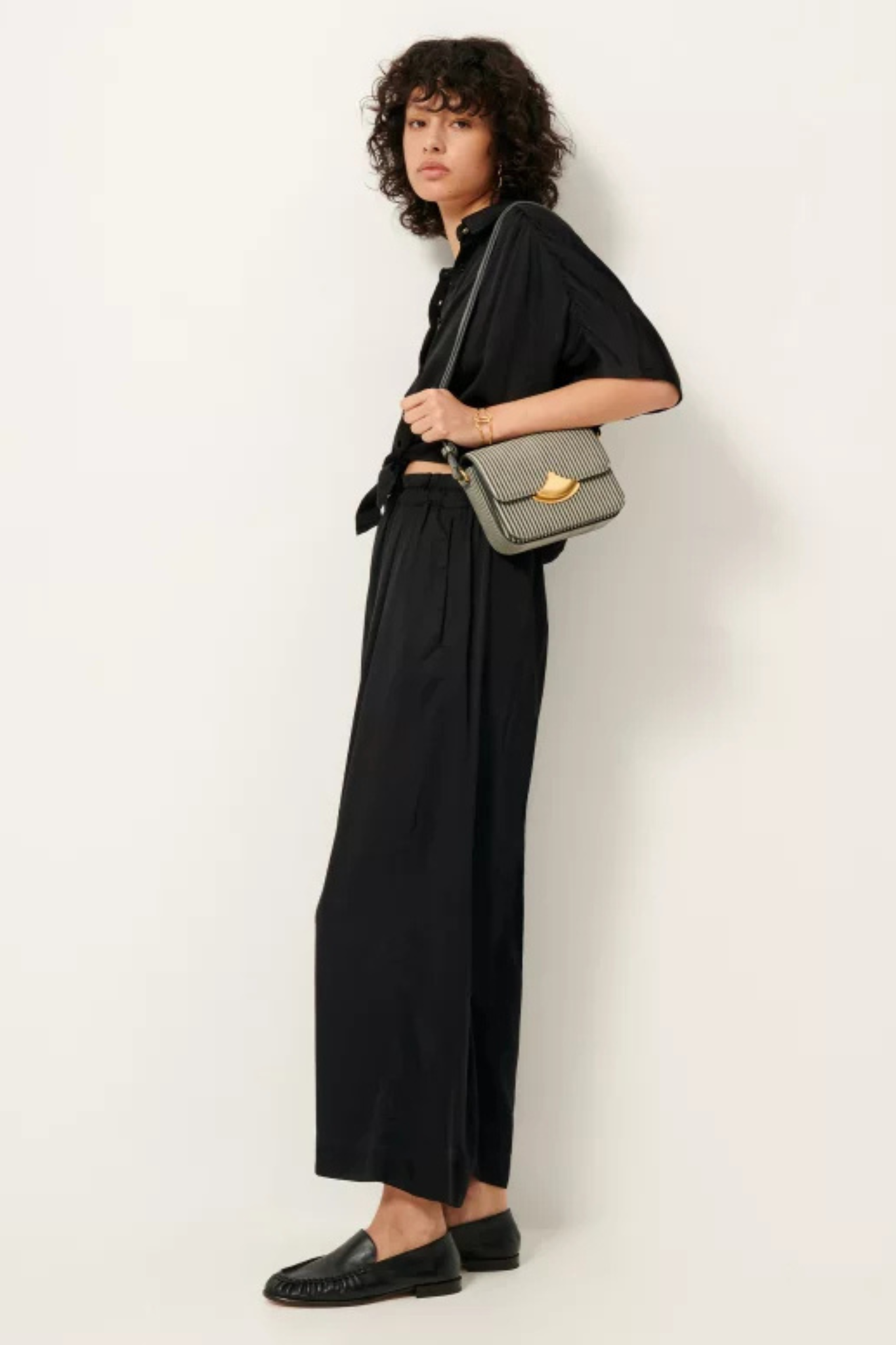 Model wearing the Sessun isla night wide leg elastic pants in black. Side view