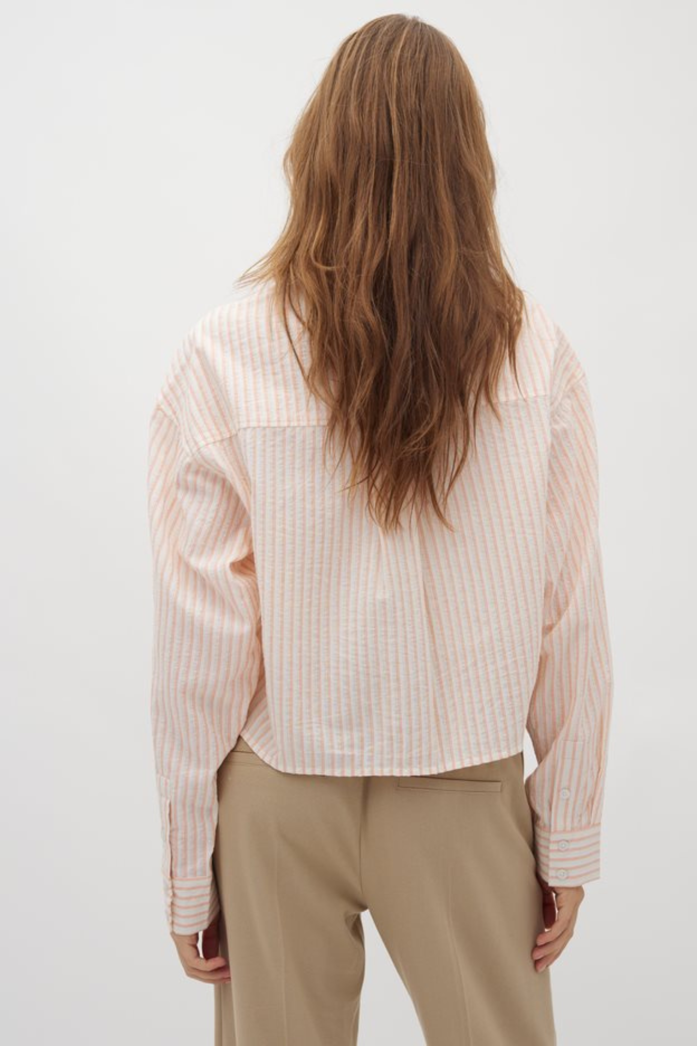 Model wearing the Mbym emmelia deserae shirt in white with orange stripes. Back view