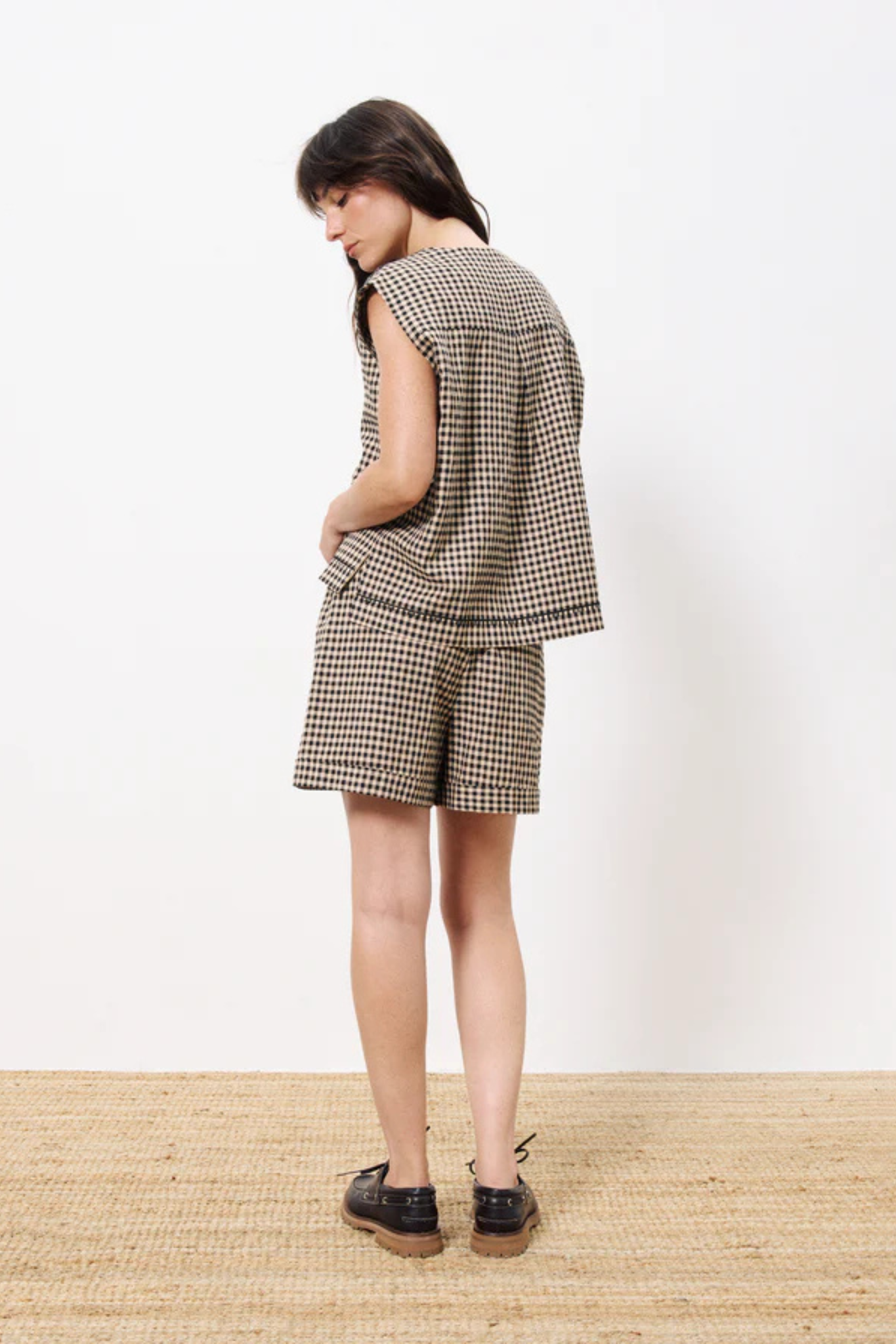 Model wearing the FRNCH adama gilet cardigan in black and beige checked. Back view