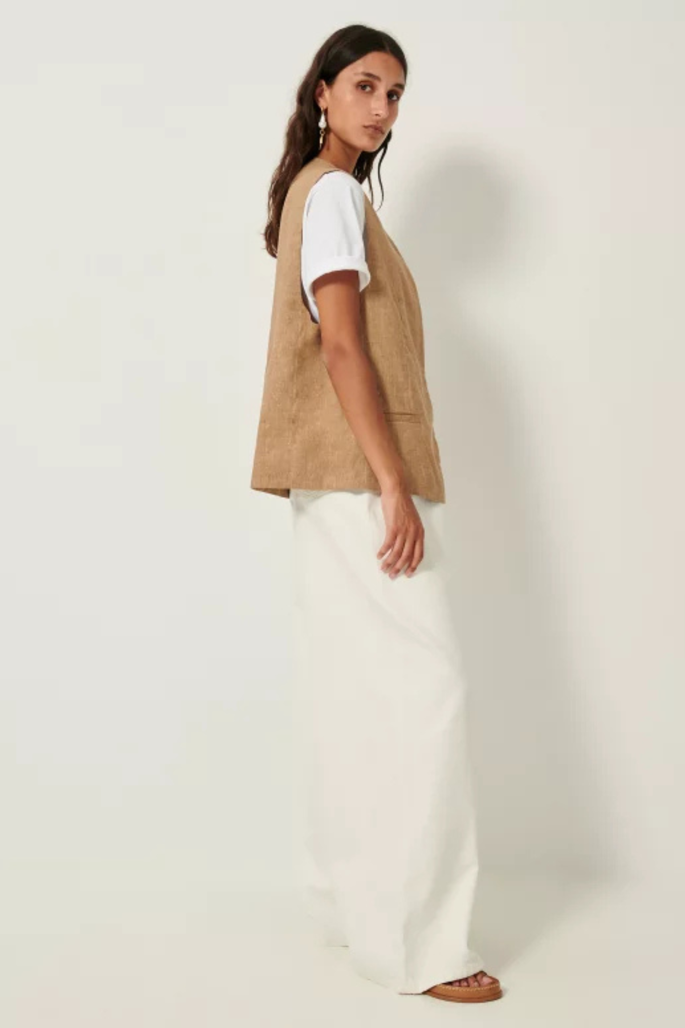 Model wearing the Sessun marcello sleeveless jacket in camel. Side view