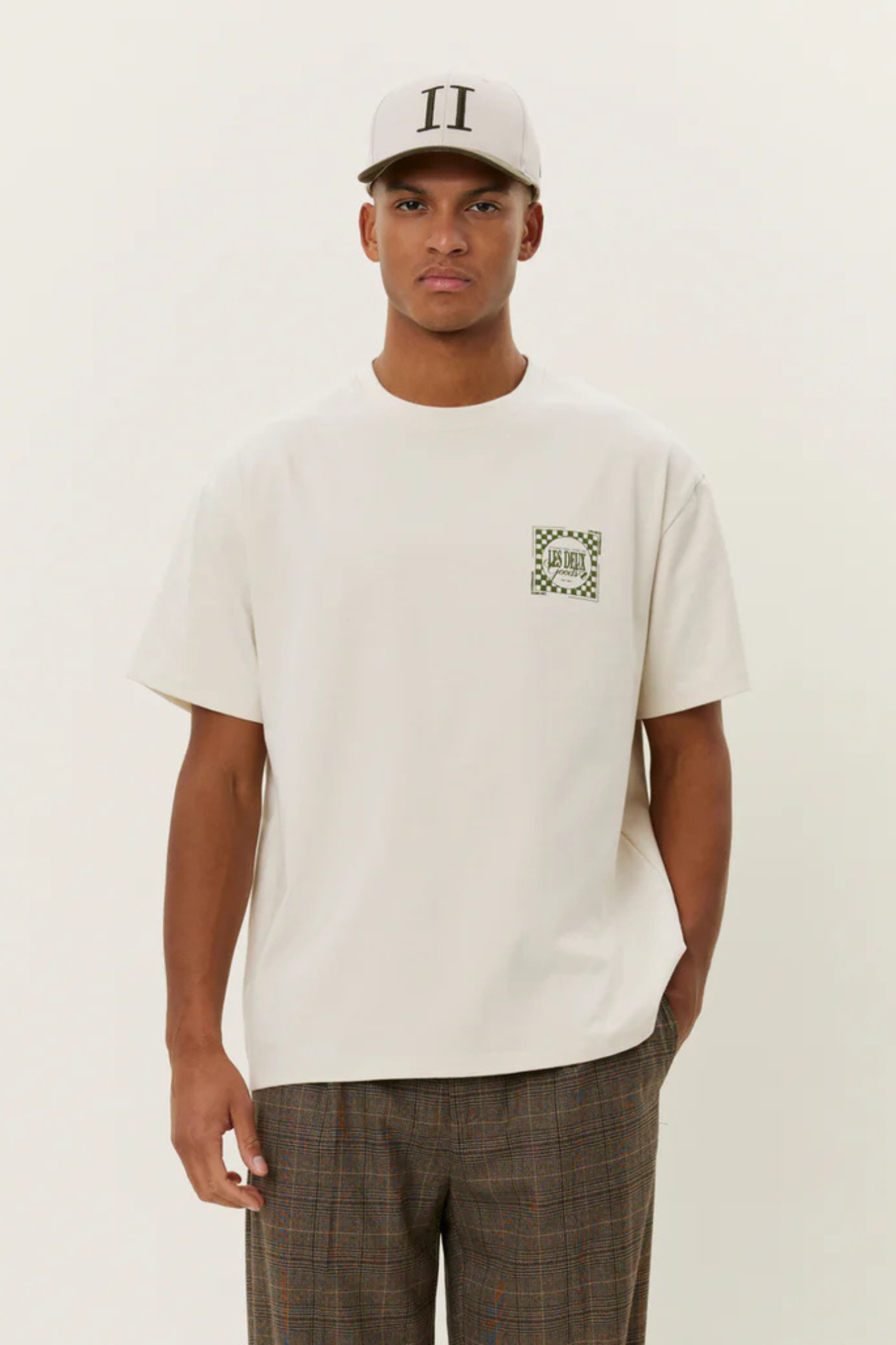 Model wearing the Les Deux goods t-shirt in ivory and green. Front view