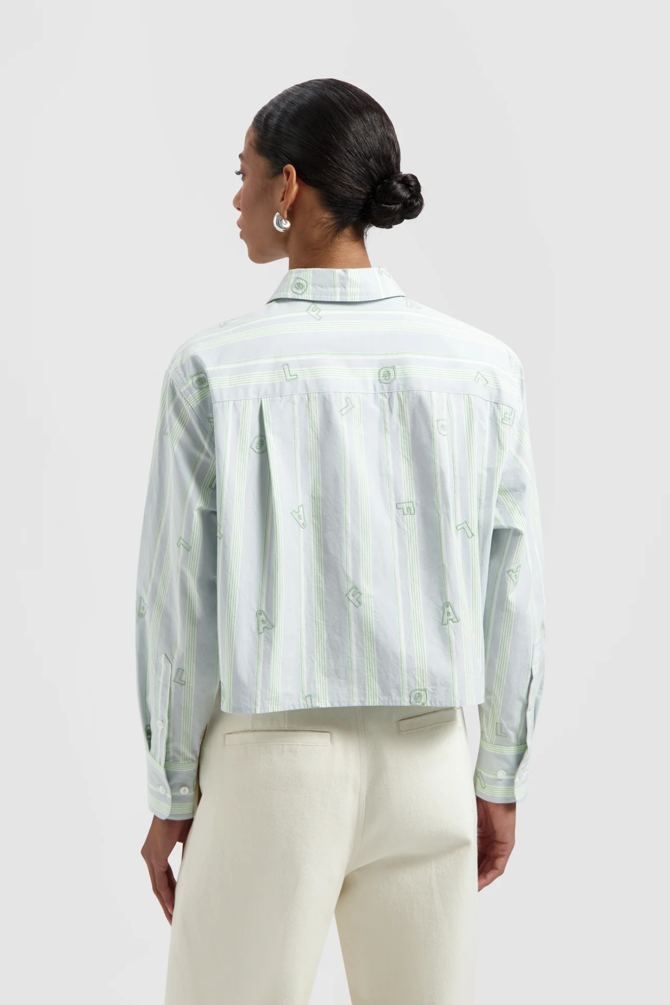 Model wearing the Olaf embro logo stripe cropped shirt in green and blue. Back view