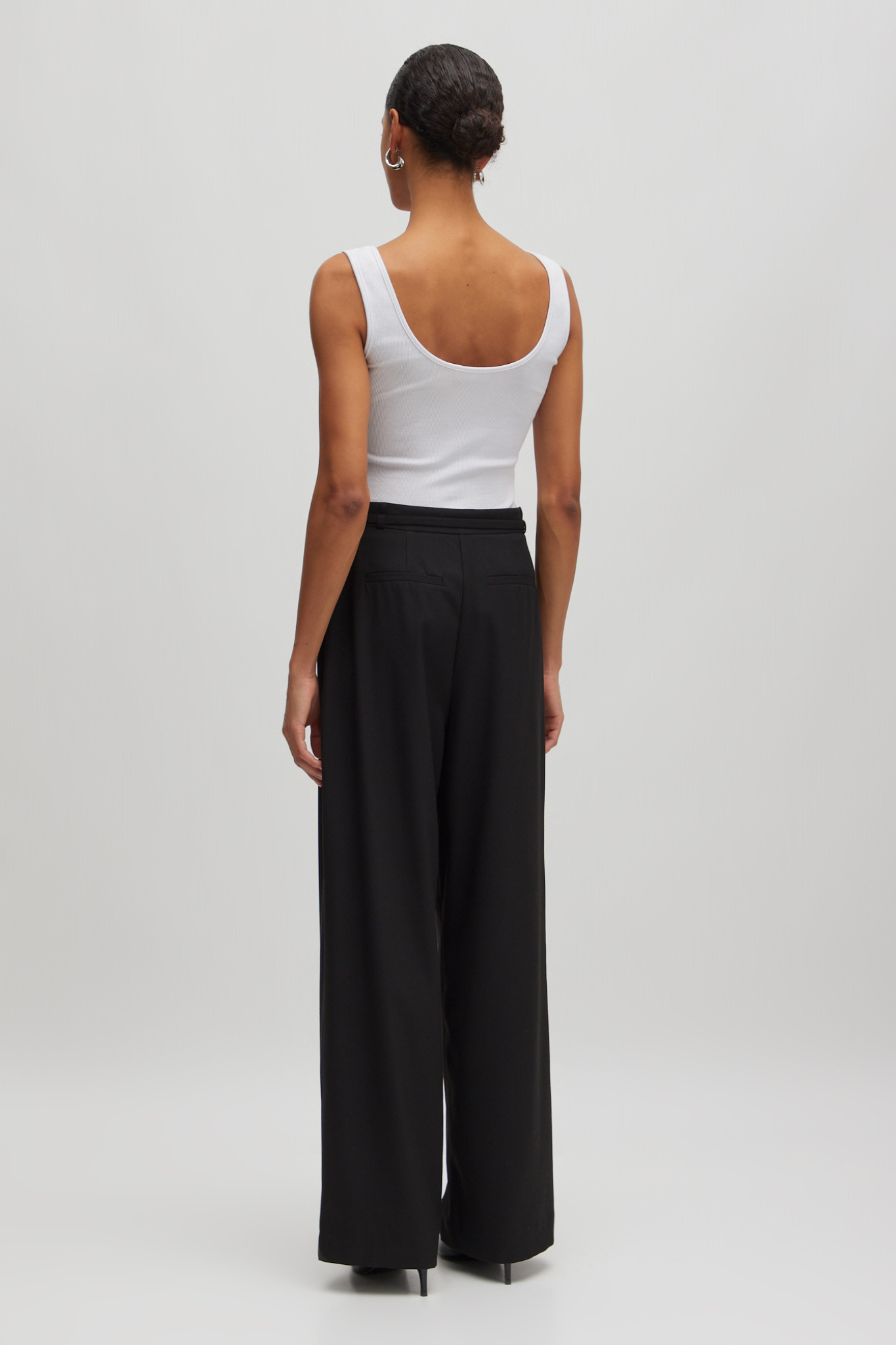 Model wearing the Edited Elna pants in black. Back view