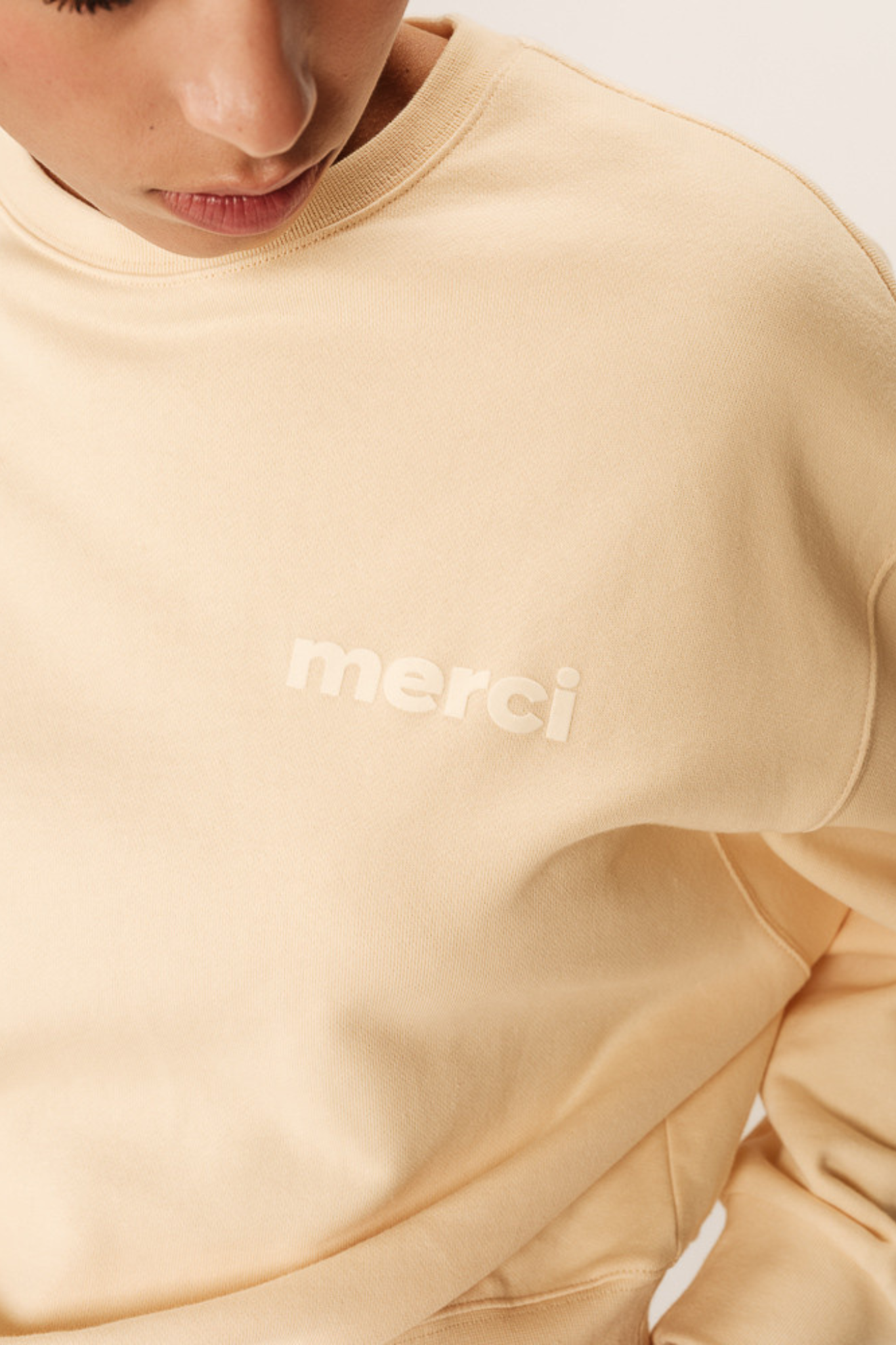 Model wearing the Grace & Mila positive merci sweater in beige. Close front view