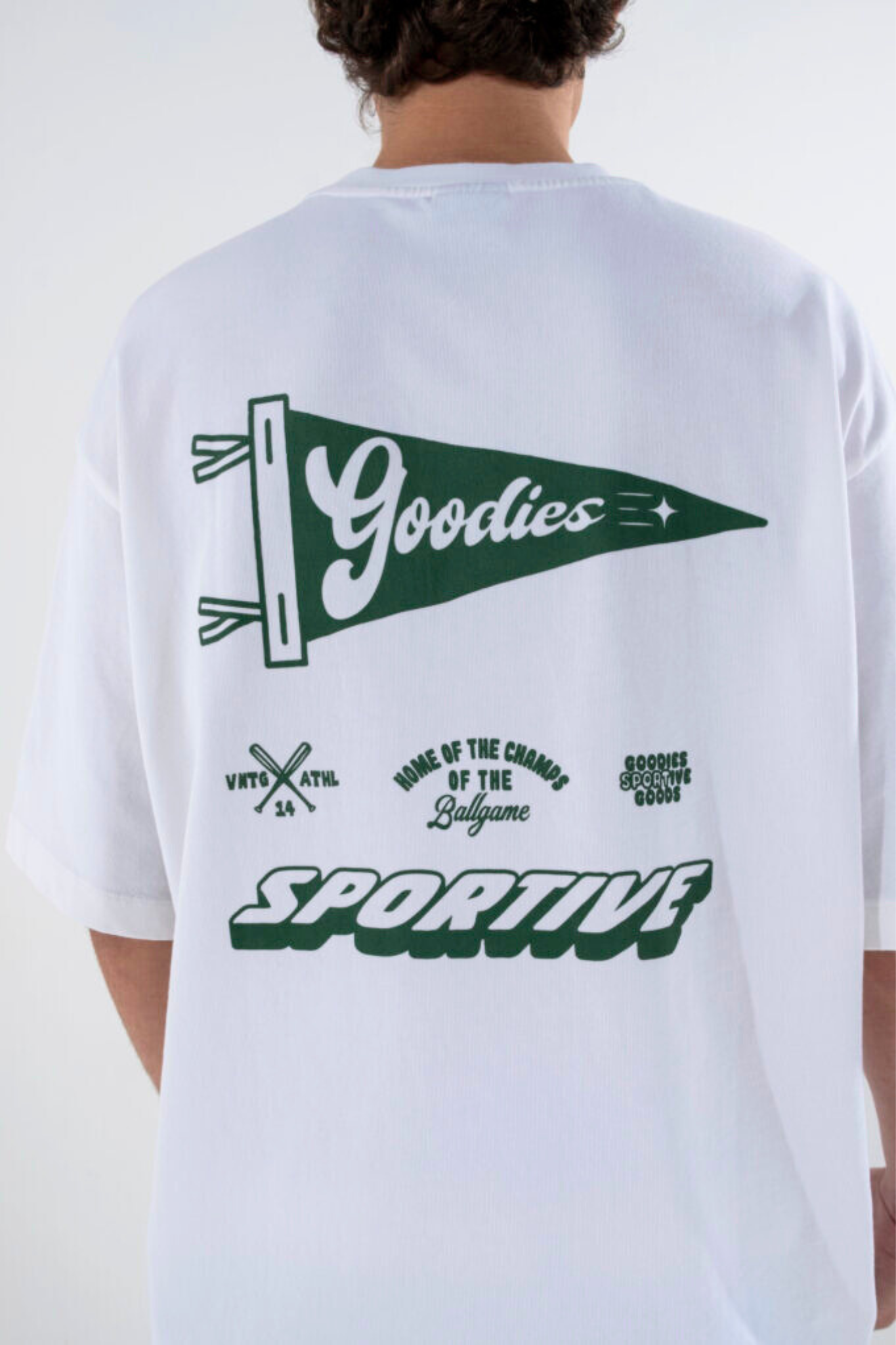 Model wearing the Goodies Sportive flag t-shirt in white and graphic in green. Back view