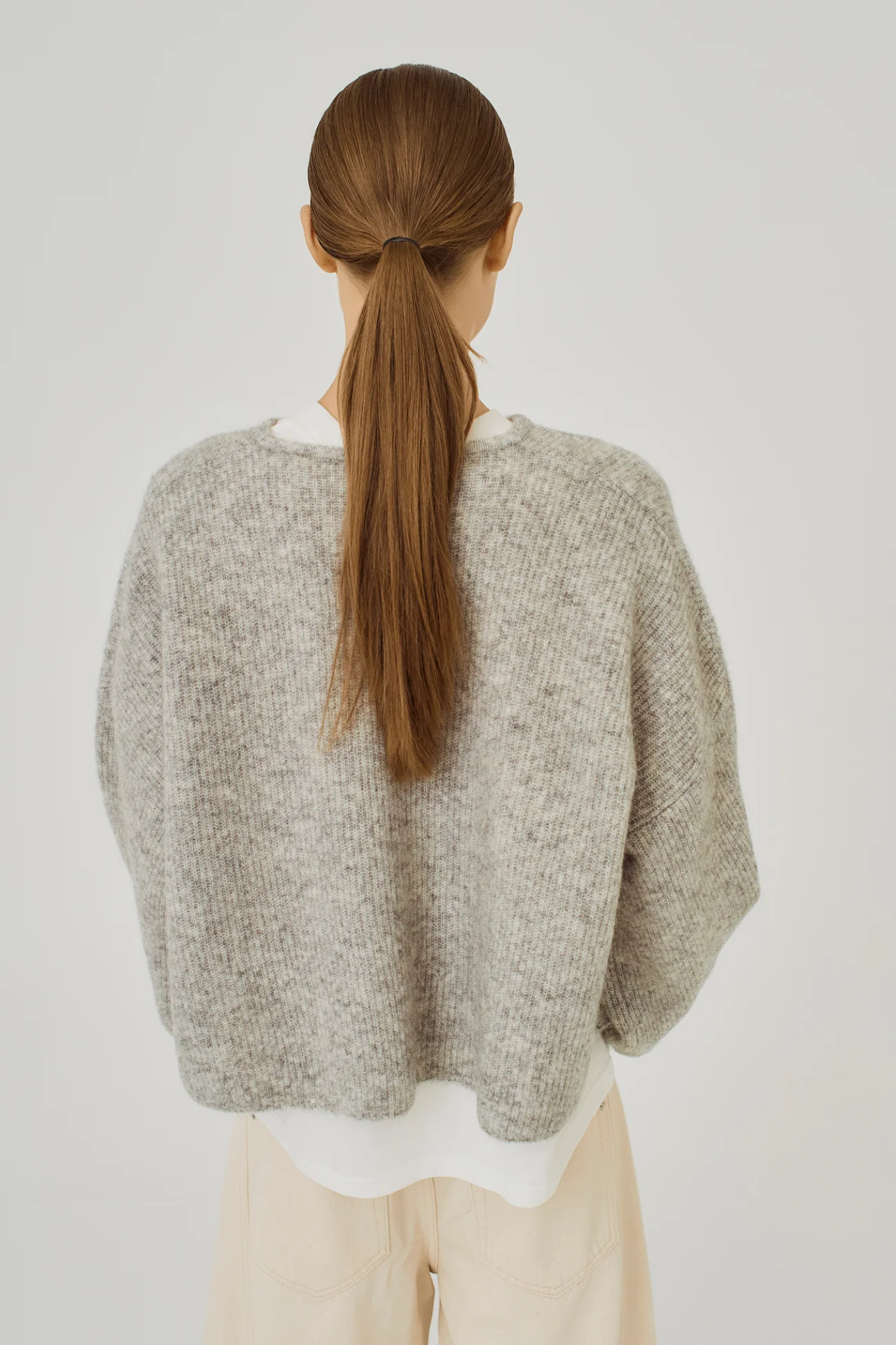 Model wearing the Norr hazina knit cardigan in light grey melange. Back view