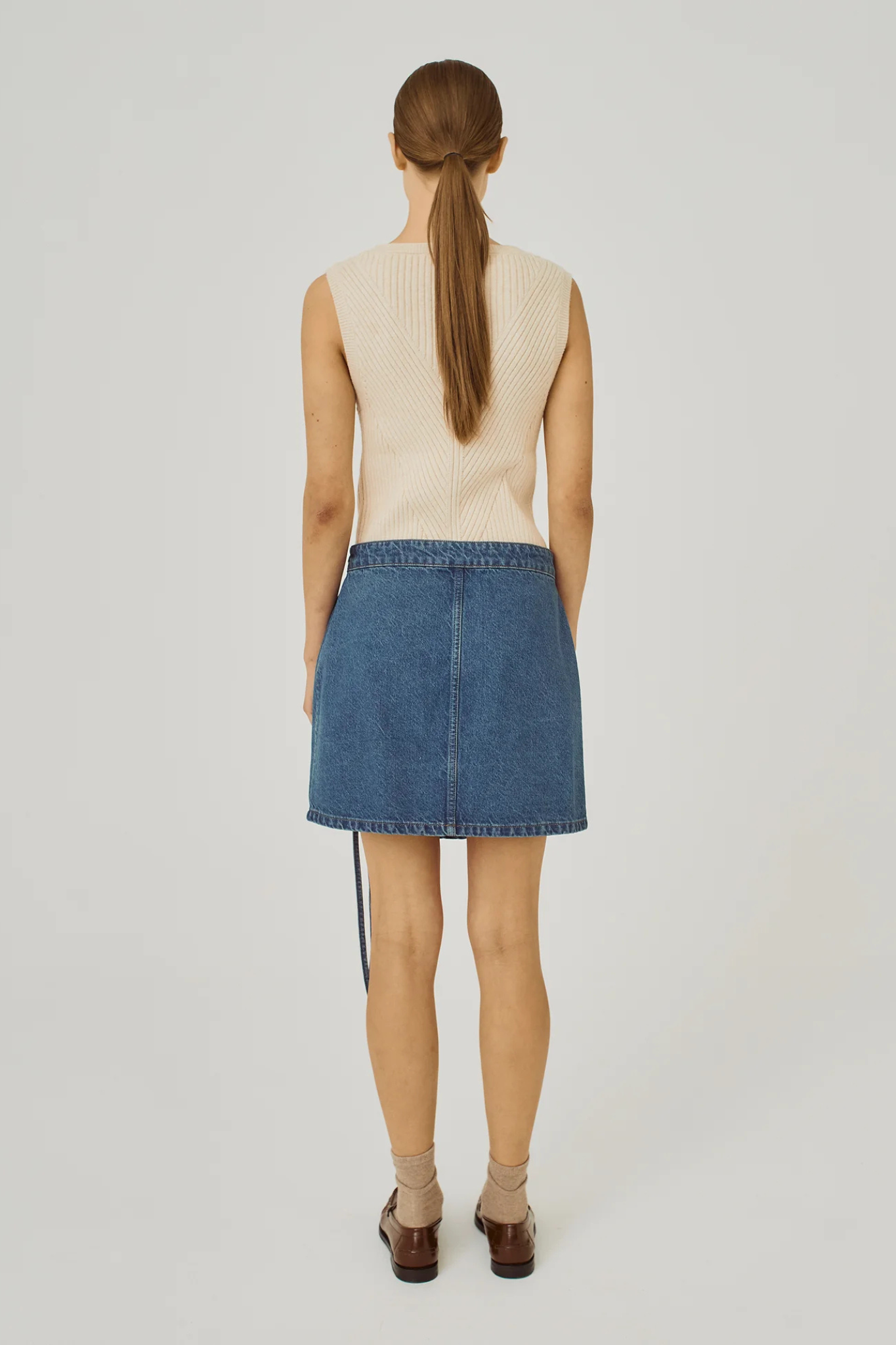 Model wearing the Norr ninni tie denim skirt in blue. Back view