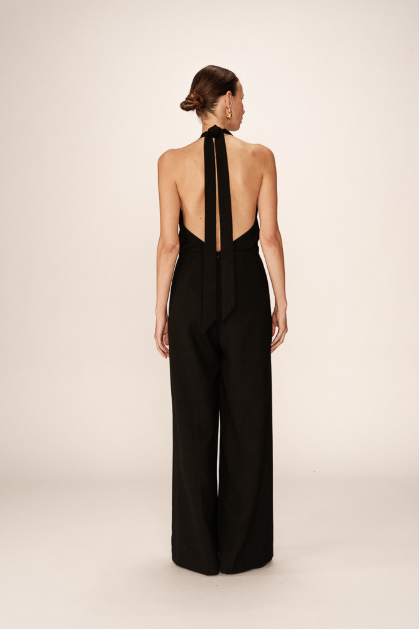 Model wearing the Grace & Mila philomene jumpsuit with open back in black. Back view