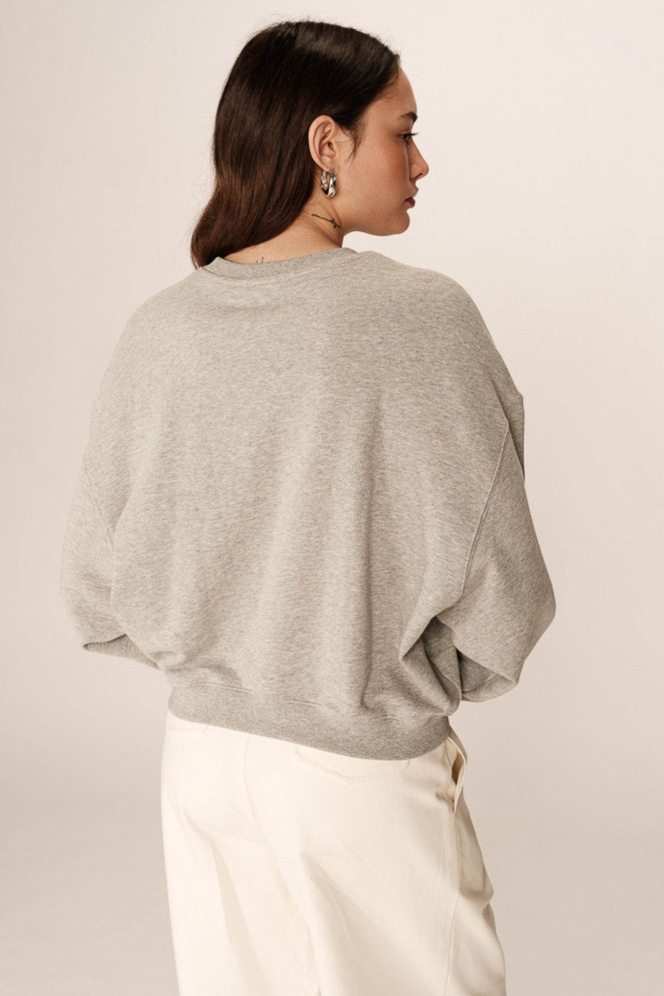 Model wearing the Grace & Mila positive merci sweater in grey. Back view