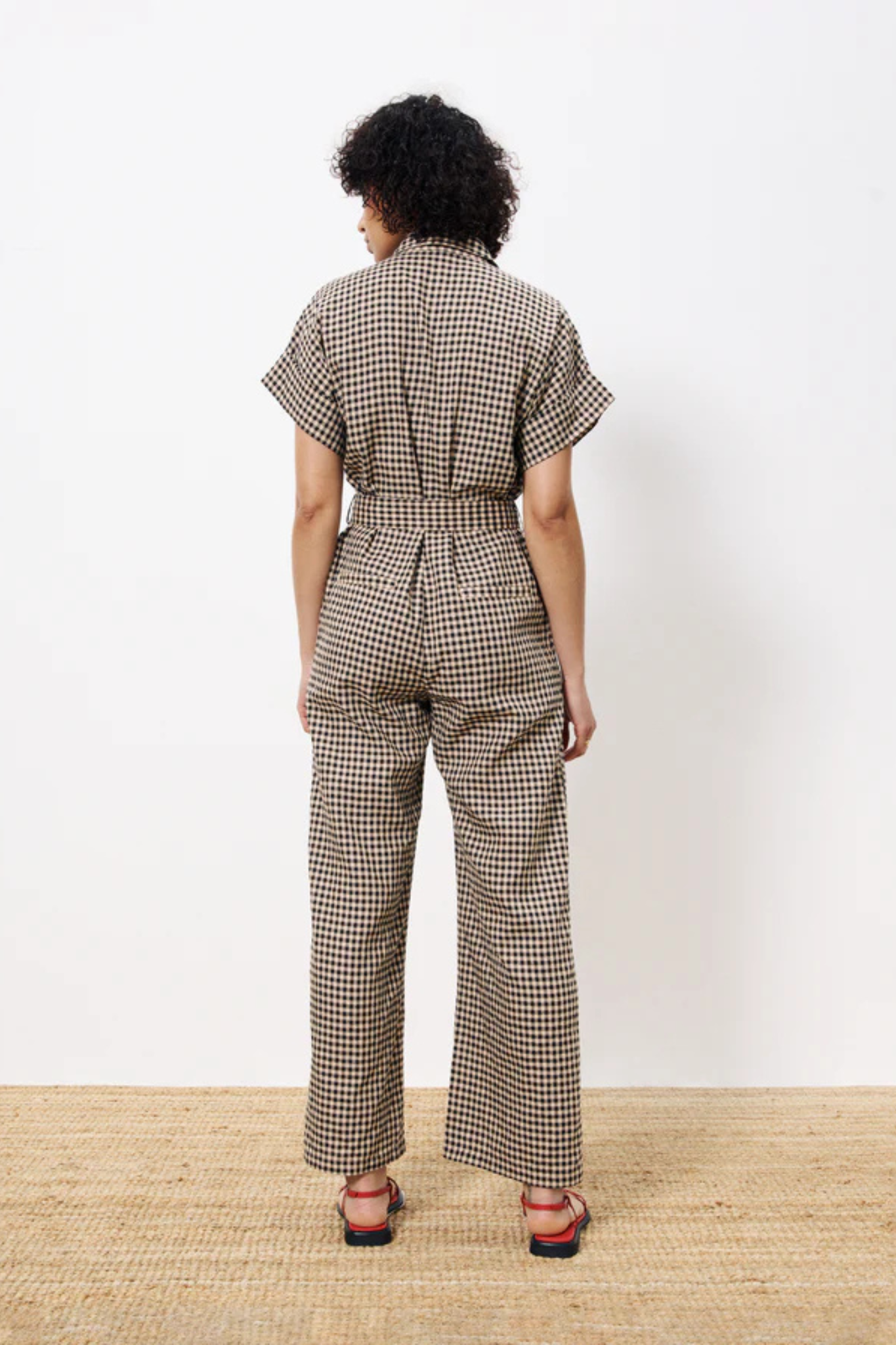 Model wearing the FRNCH elfie jumpsuit in black and beige checked. Back view