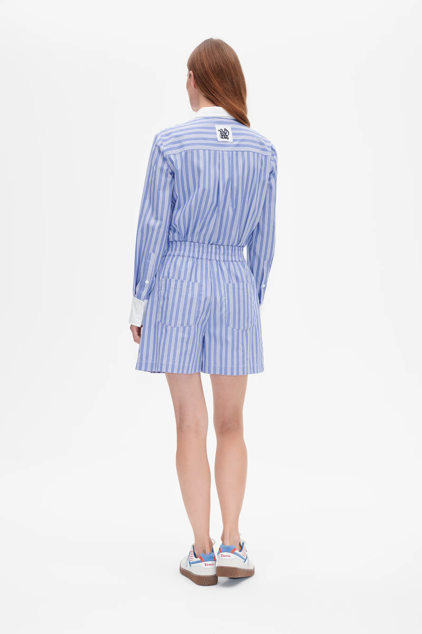 Model wearing the Baum Und Pferdgarten natie short in blue and white striped. Back view