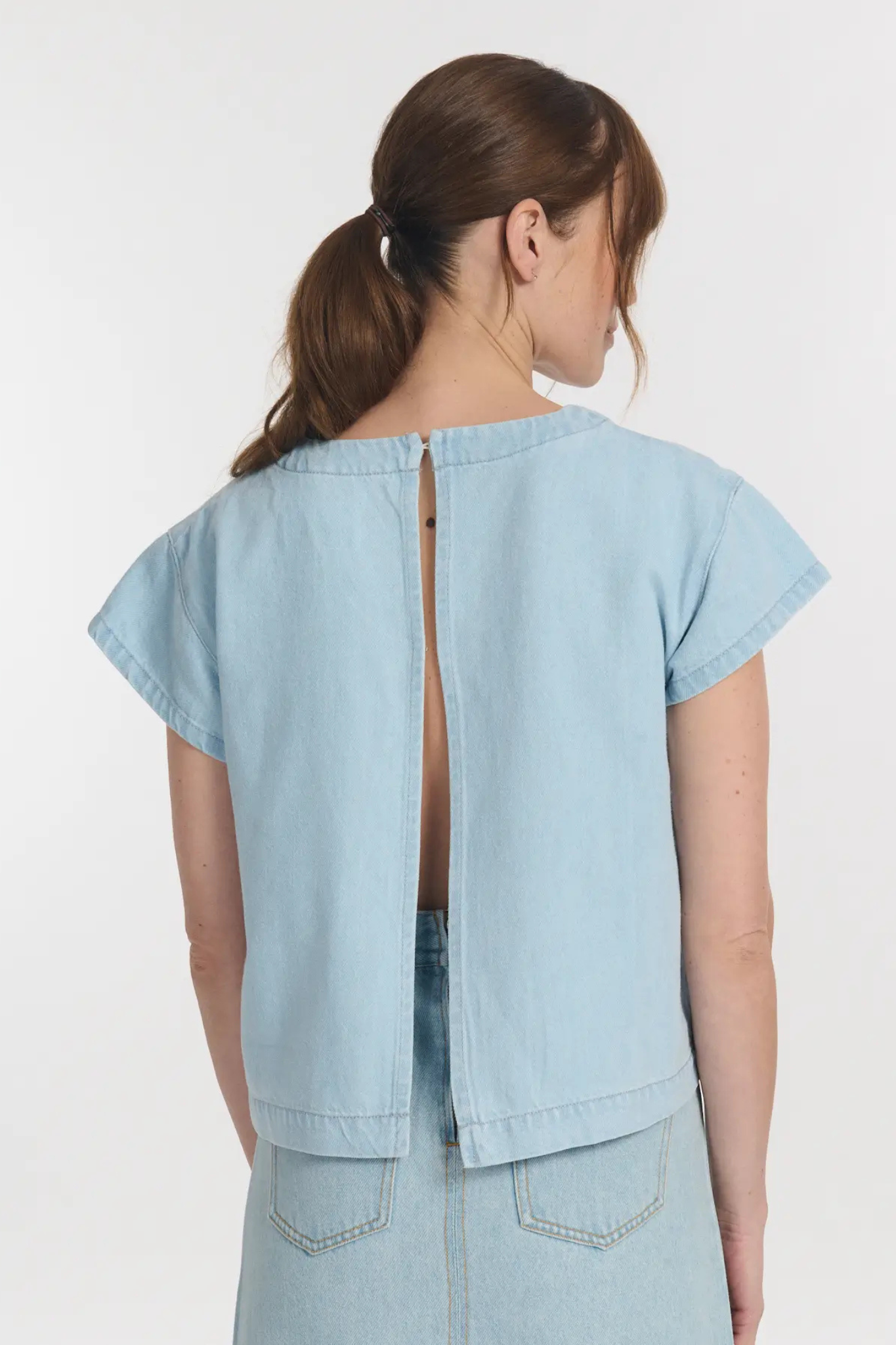 Model wearing the Labdip clio top loose with open back in bleach. Back view