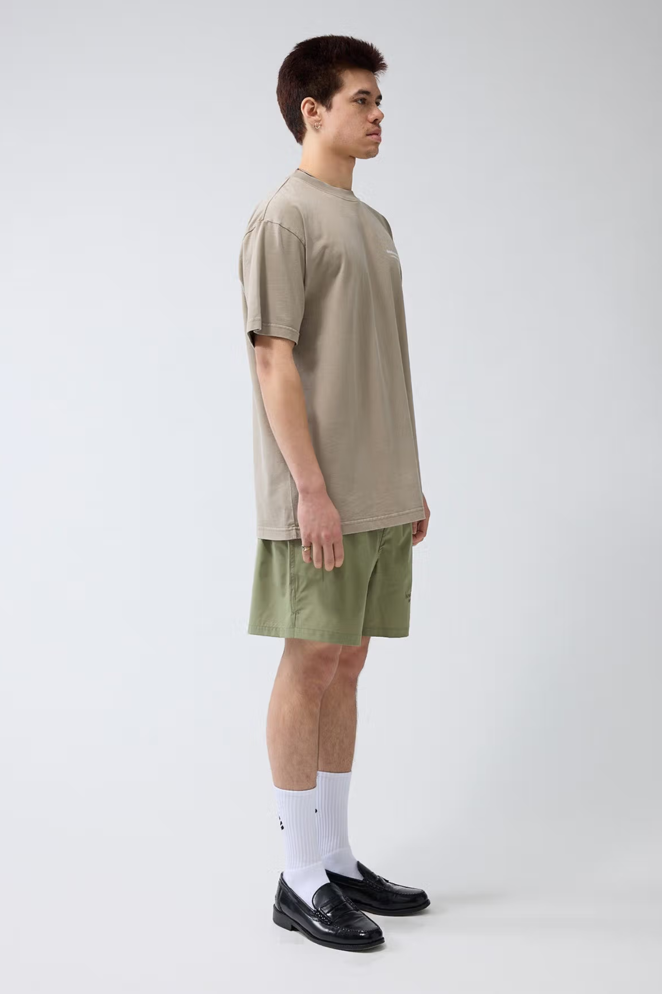 Model wearing the New Amsterdam seal beige t-shirt with logo in white. Side view