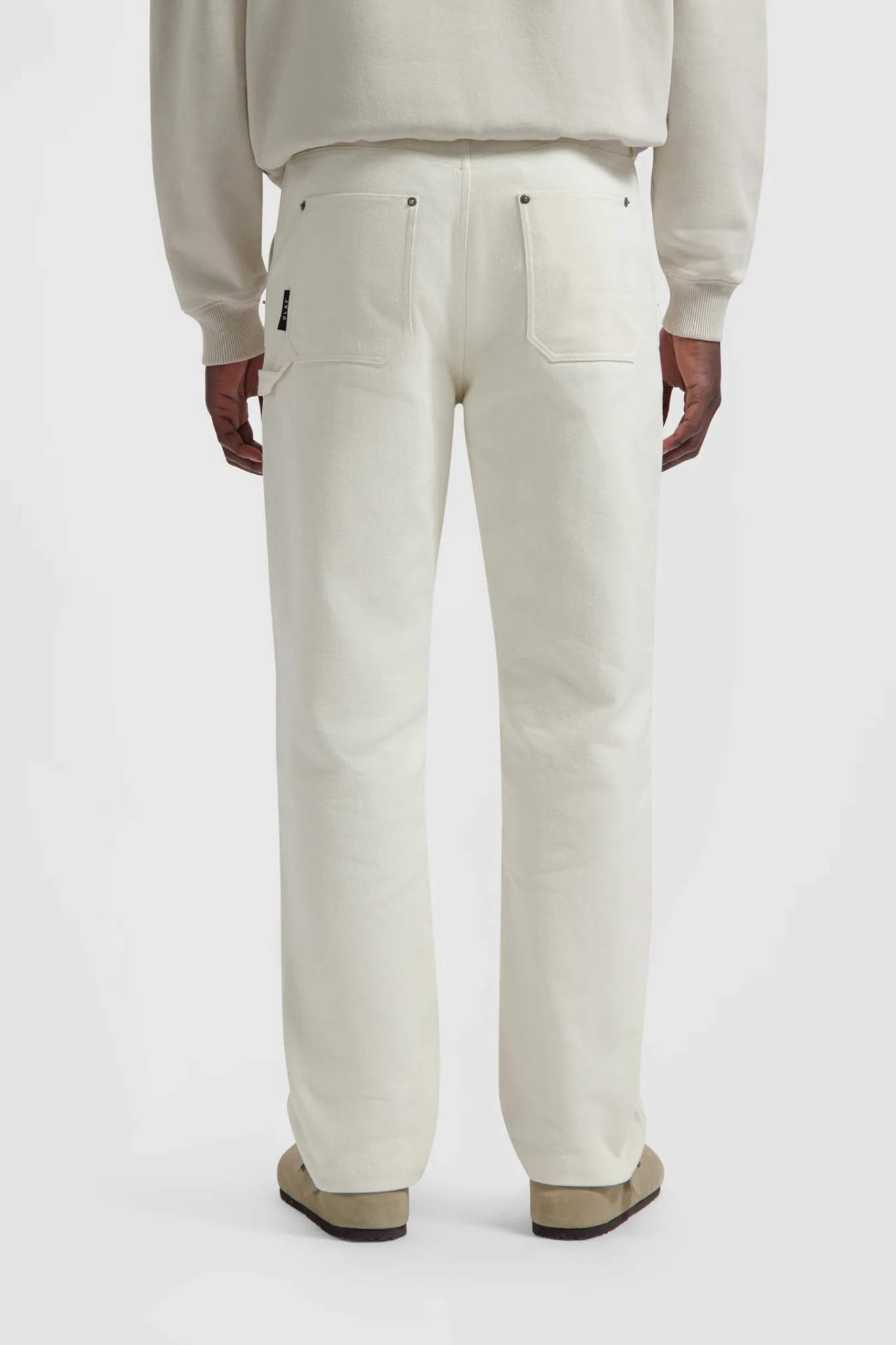 Model wearing the Olaf workwear pants in off-white. Back view