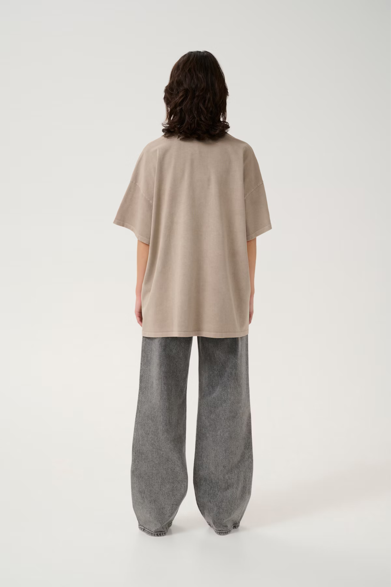 Model wearing the Gestuz jio oversized t-shirt in beige brown. Back view