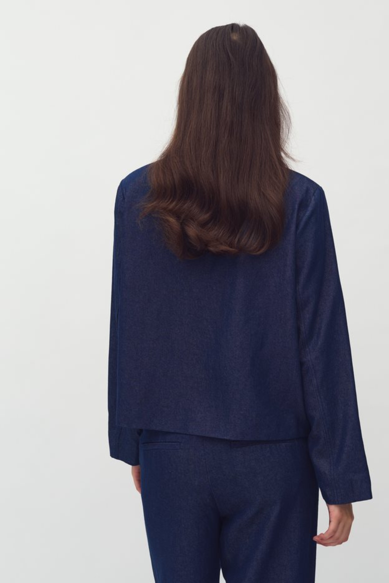 Model wearing the Mbym yoshi magnolia blazer in dark denim. Back view