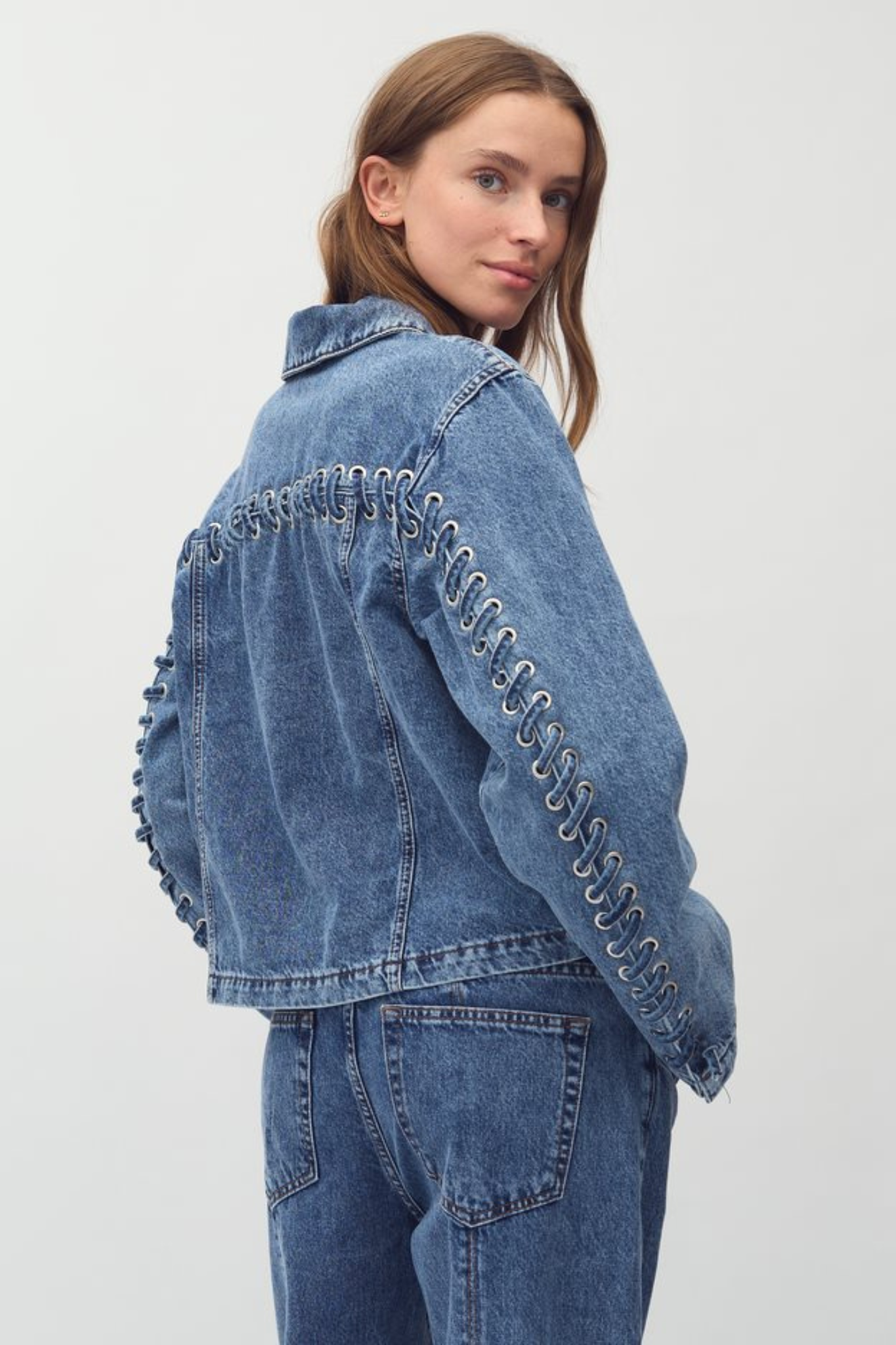 Model wearing the Mbym zolan fabrt jeans jacket in mid blue vintage. Back view