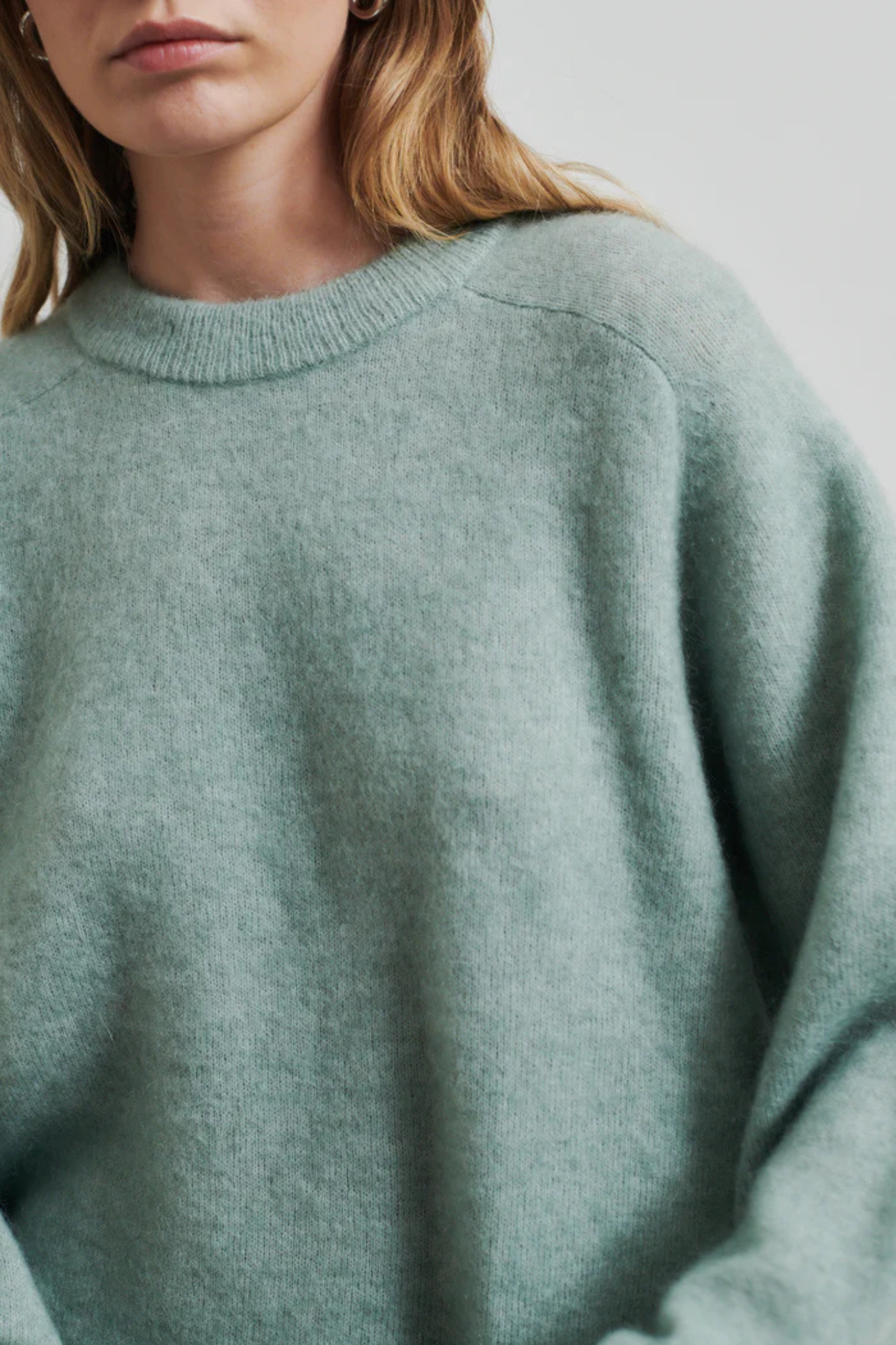 Model wearing the Second Female brookline raglan o-neck knit in green. Close front view