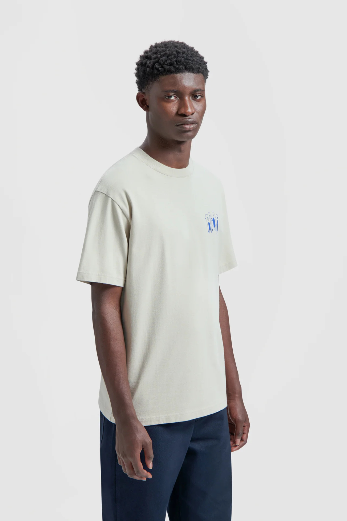 Model wearing the Olaf smudge logo t-shirt in beige and logo in blue. Side view