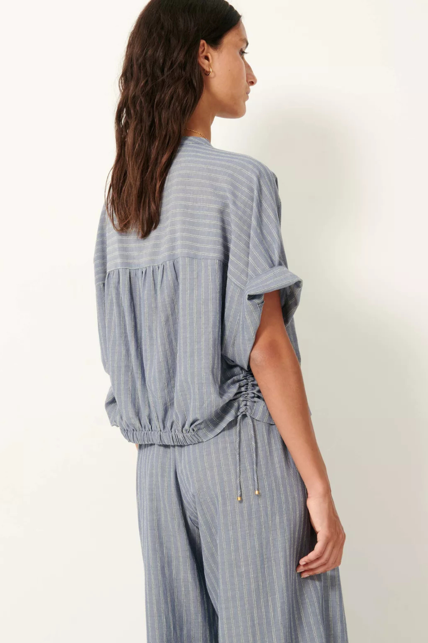 Model wearing the Sessun reva blouse in chambray blue. Back view