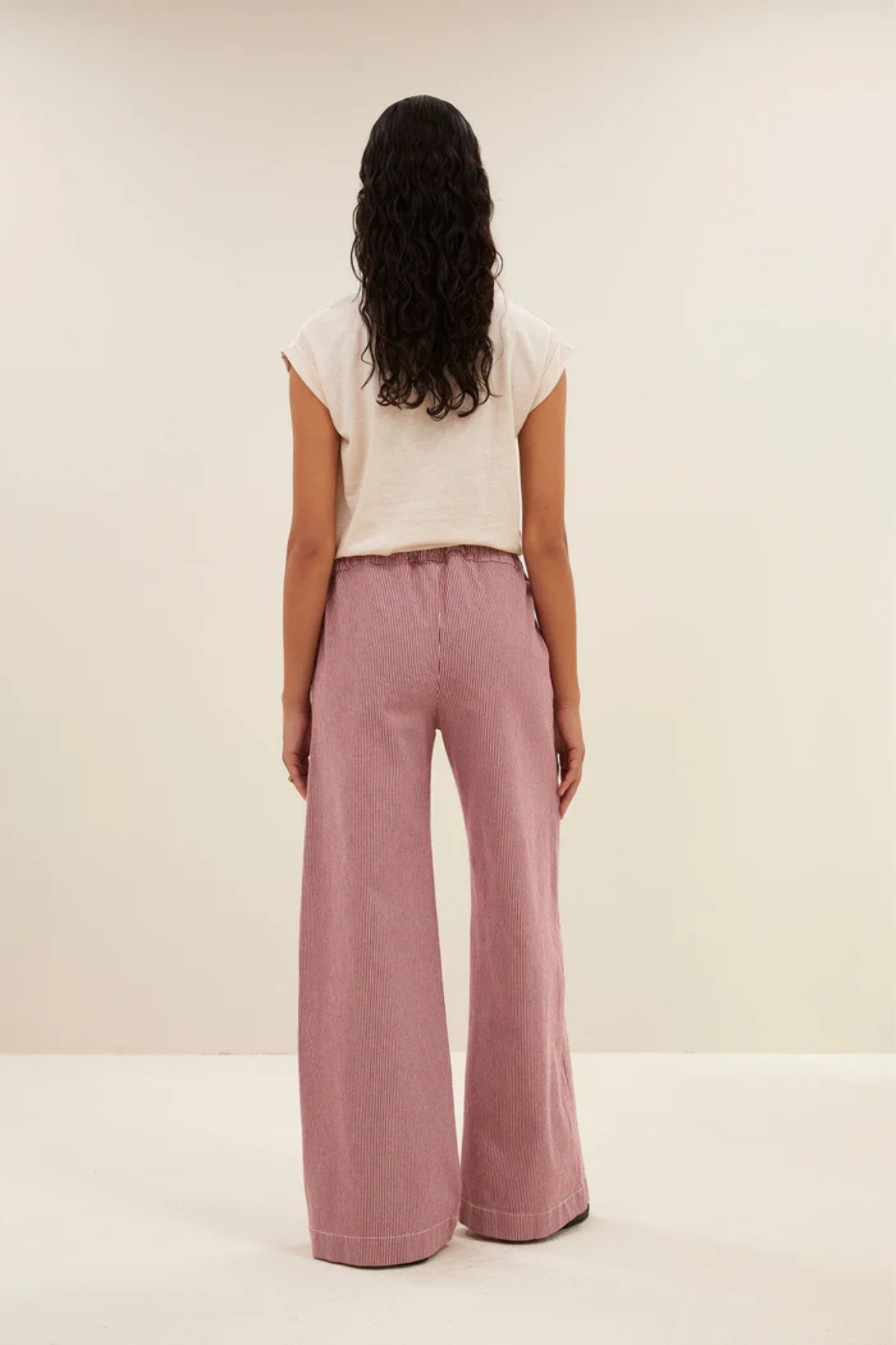 Model wearing the By-Bar Neal striped pants in pink and white. Back view