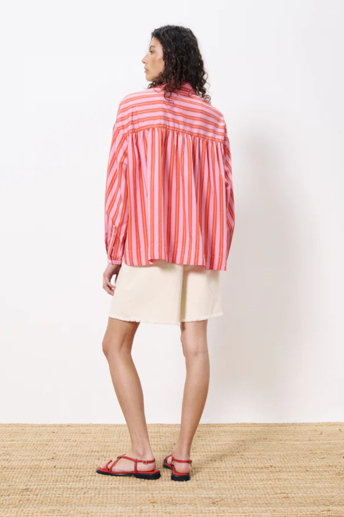 Model wearing the FRNCH catheline shirt in pink and orange striped. Back view