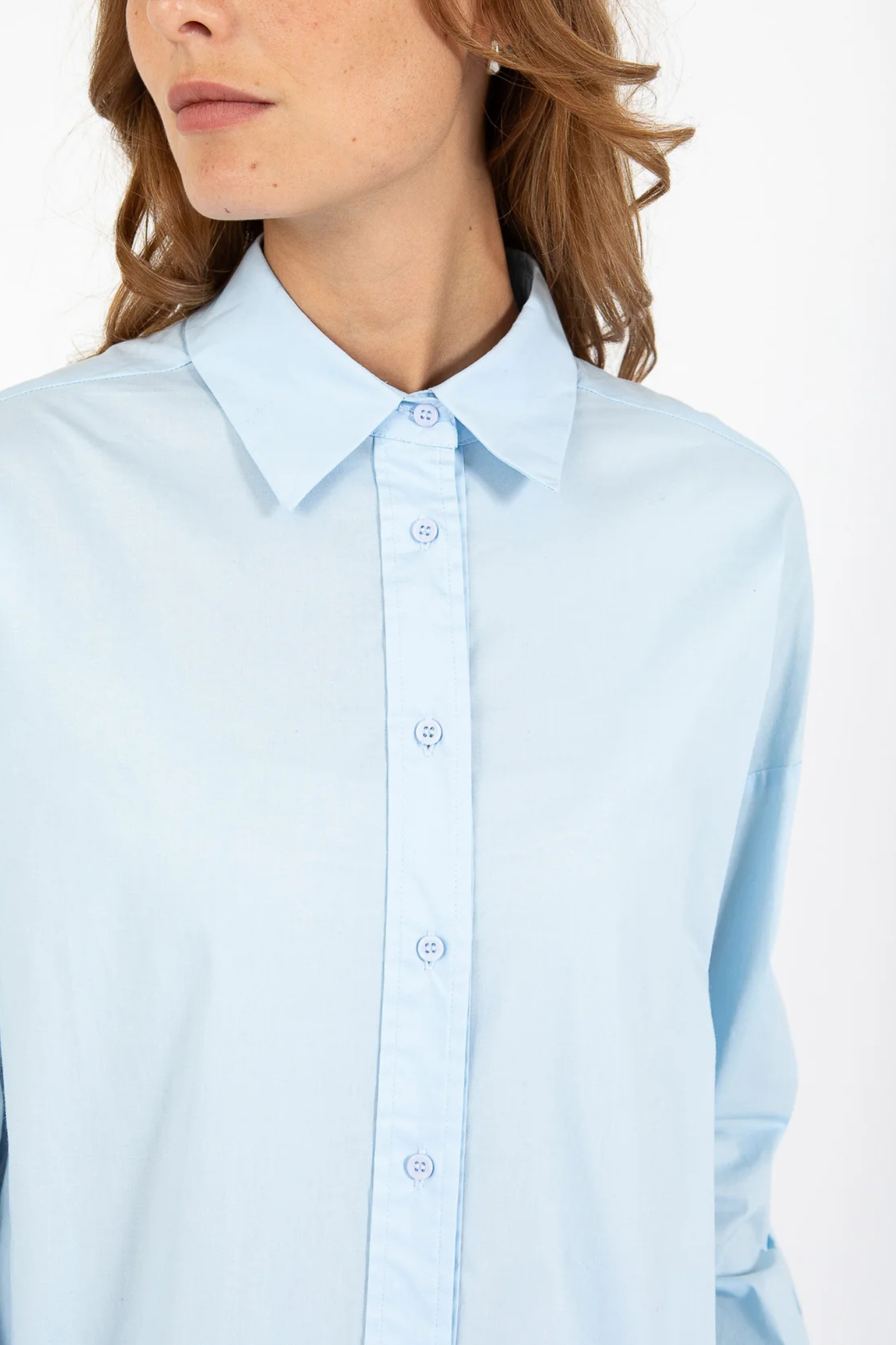 Model wearing the CC Heart millie solid loose shirt in light blue. Close front view