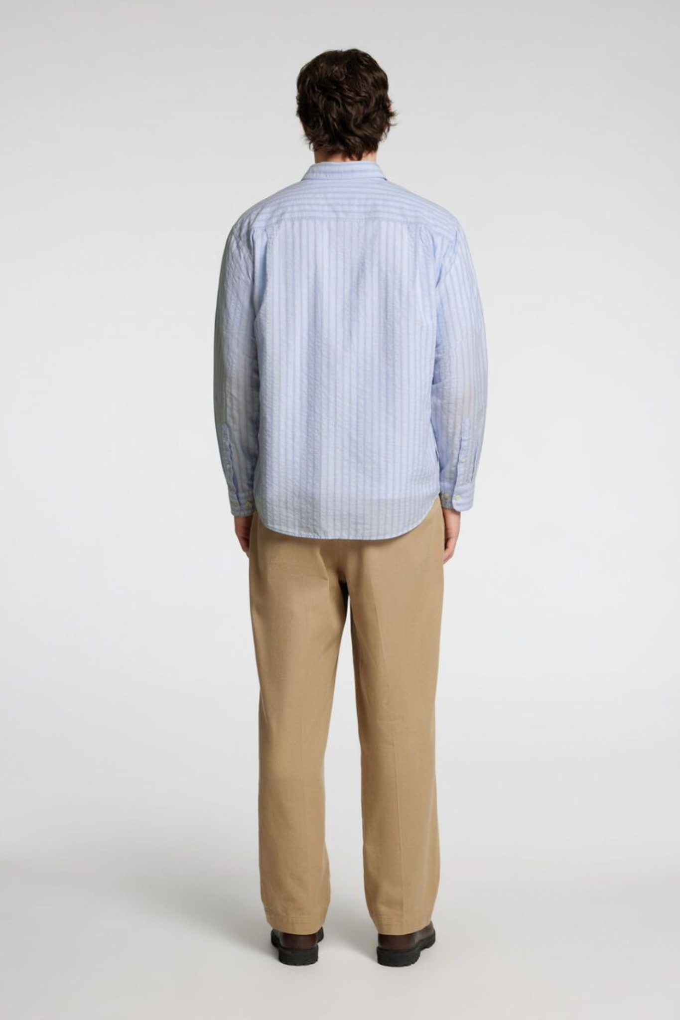 Model wearing the Selected Homme relax wilfred seersucker shirt in blue stripe. Back view