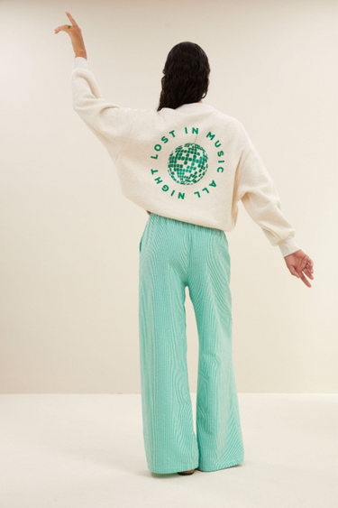 Model wearing the By-Bar bibi disco sweater in beige with letters in green. Back view