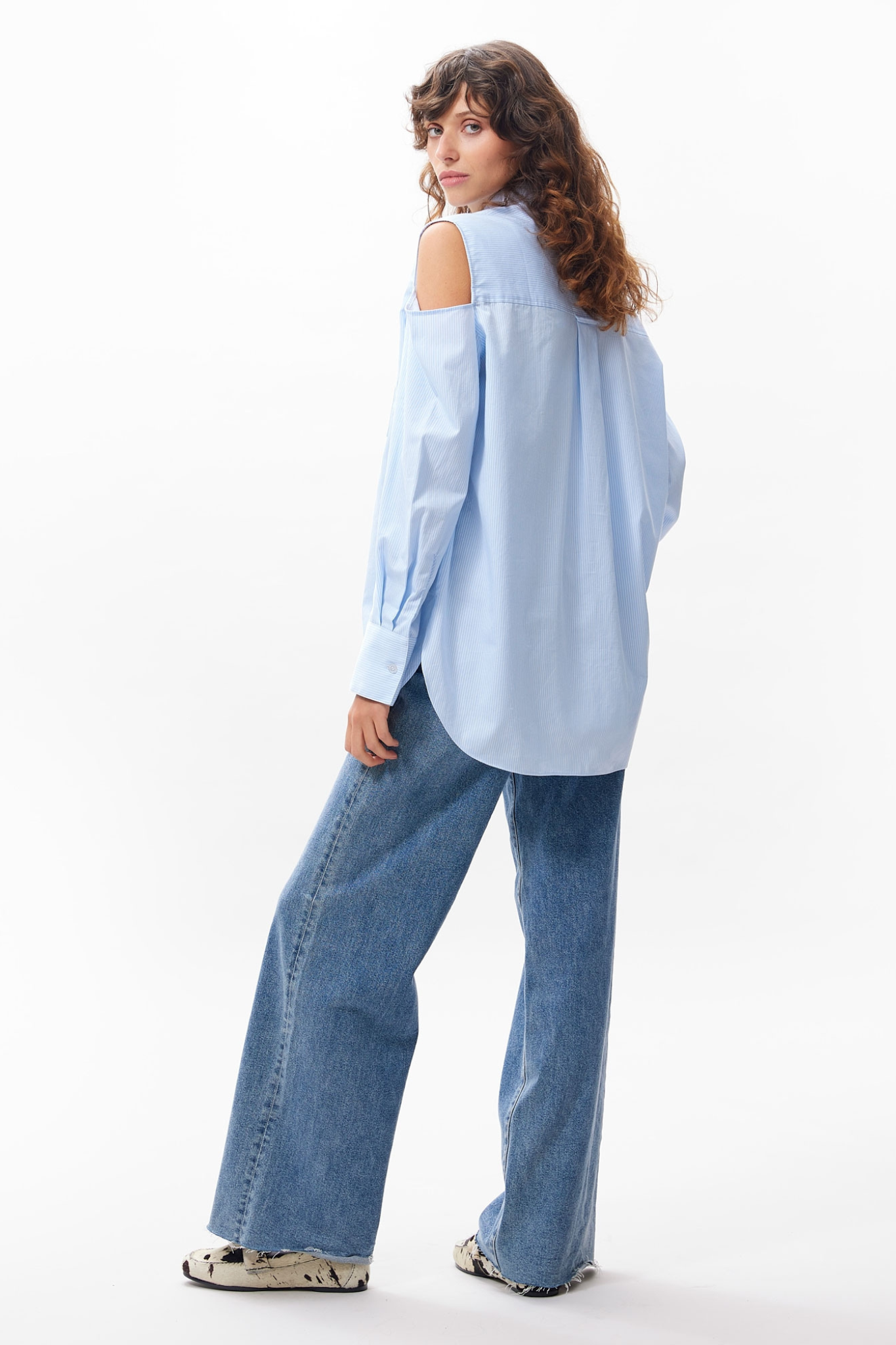 Model wearing the Catwalk Junkie open shoulder blouse in blue. Side view