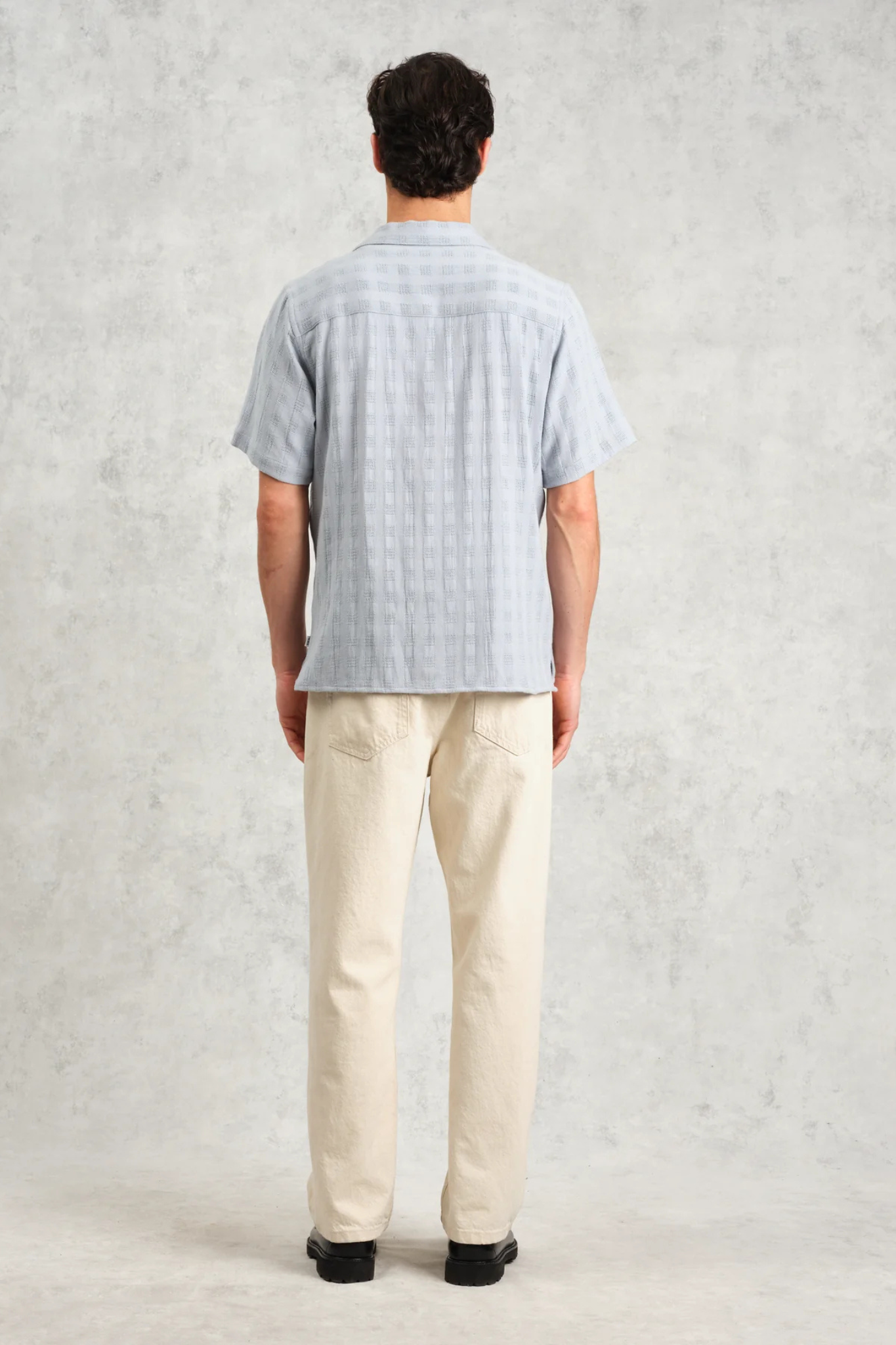 Model wearing the Wax London didcot box open weave grid shirt in pale blue. Back view 