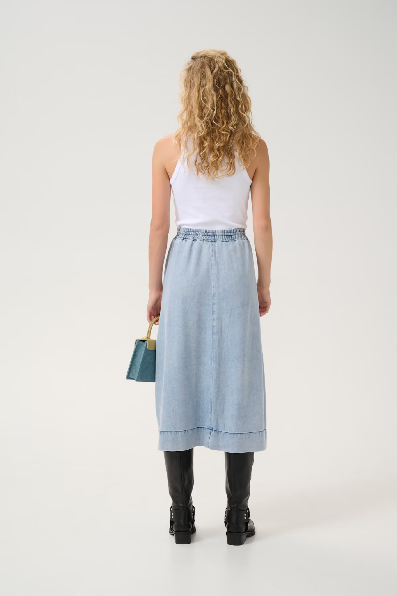 Model wearing the Gestuz felina long skirt in light blue washed. Back view