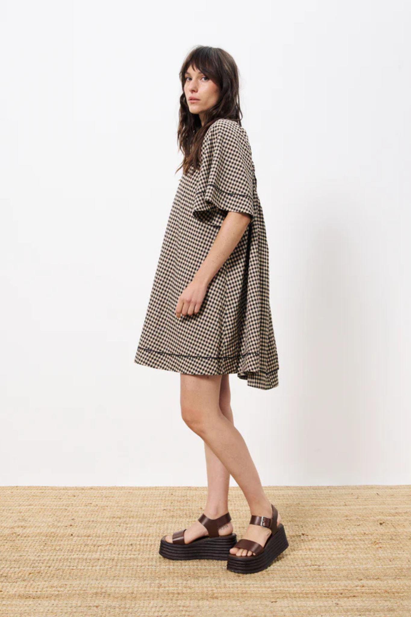 Model wearing the FRNCH afida dress in black and beige checked. Side view