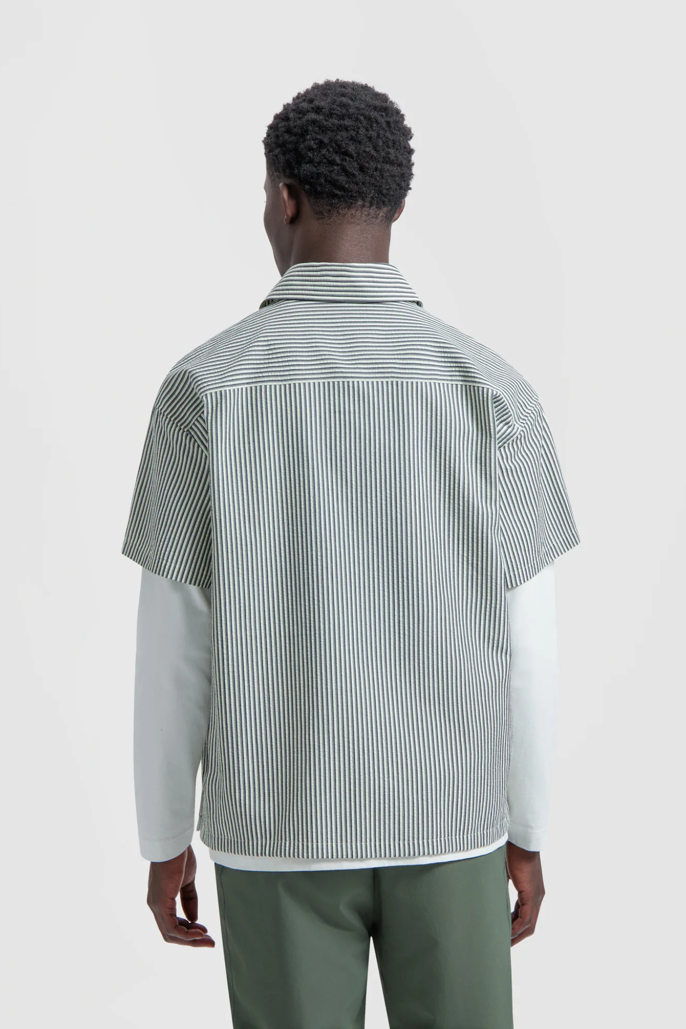 Model wearing the Olaf boxy seersucker stripe shirt in white and green. Back view