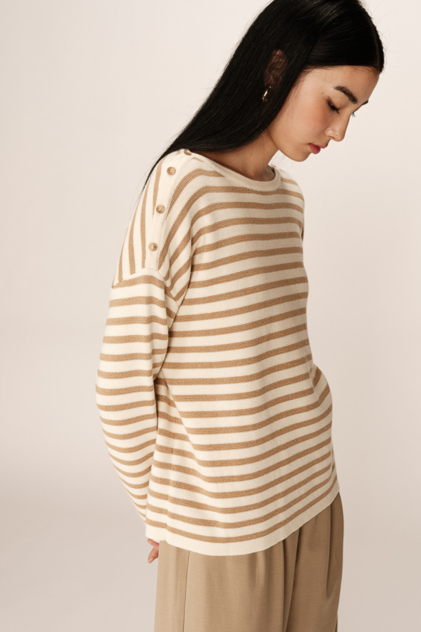 Model wearing the Grace & Mila pachamama sweater in gold and beige. Side view