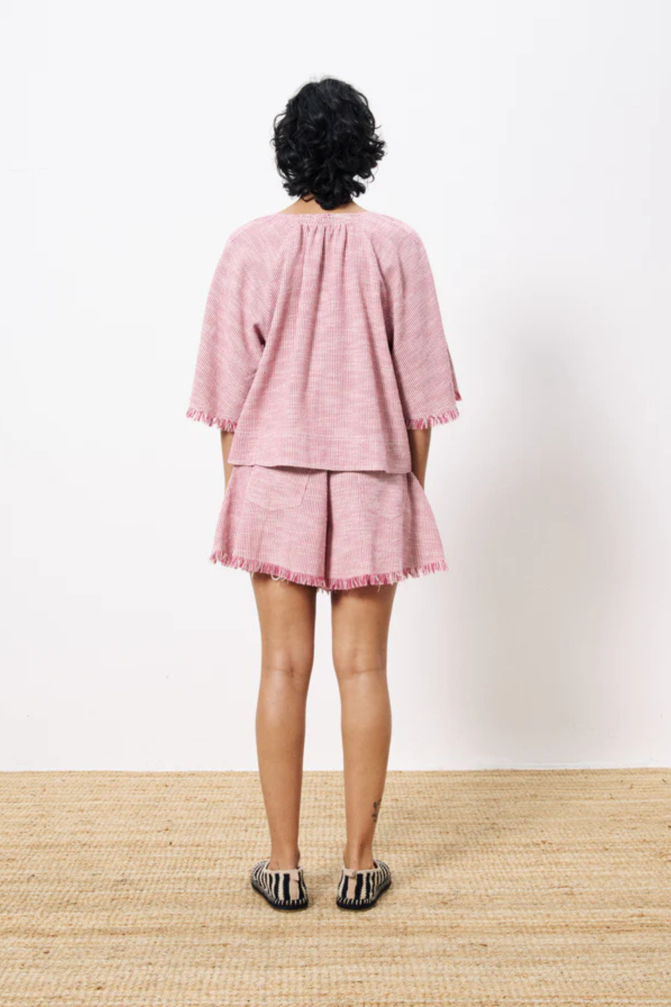 Model wearing the FRNCH alyssia blouse in fuchsia and white. Back view