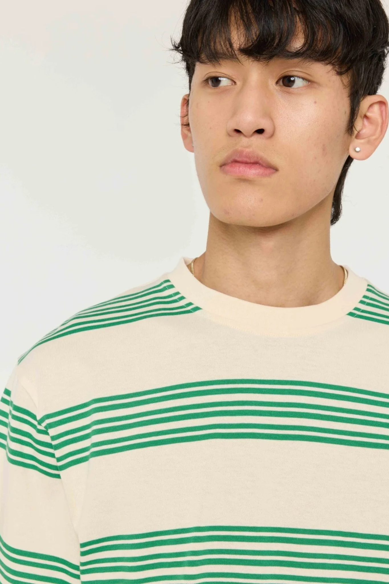 Model wearing the Castart haruto striped t-shirt in green and ecru. Front view