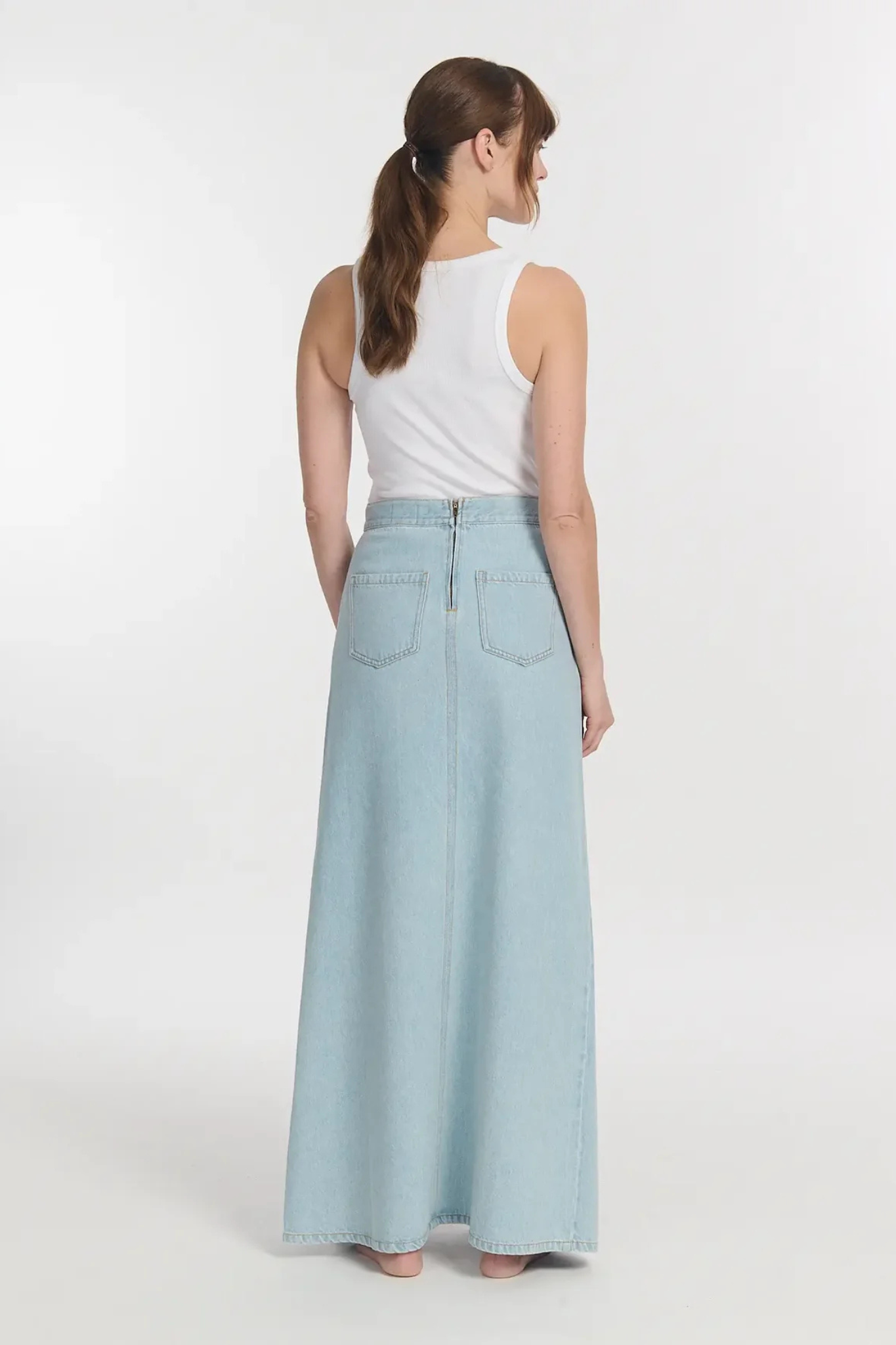 Model wearing the Labdip jodie denim tencel skirt in bleached denim. Back view