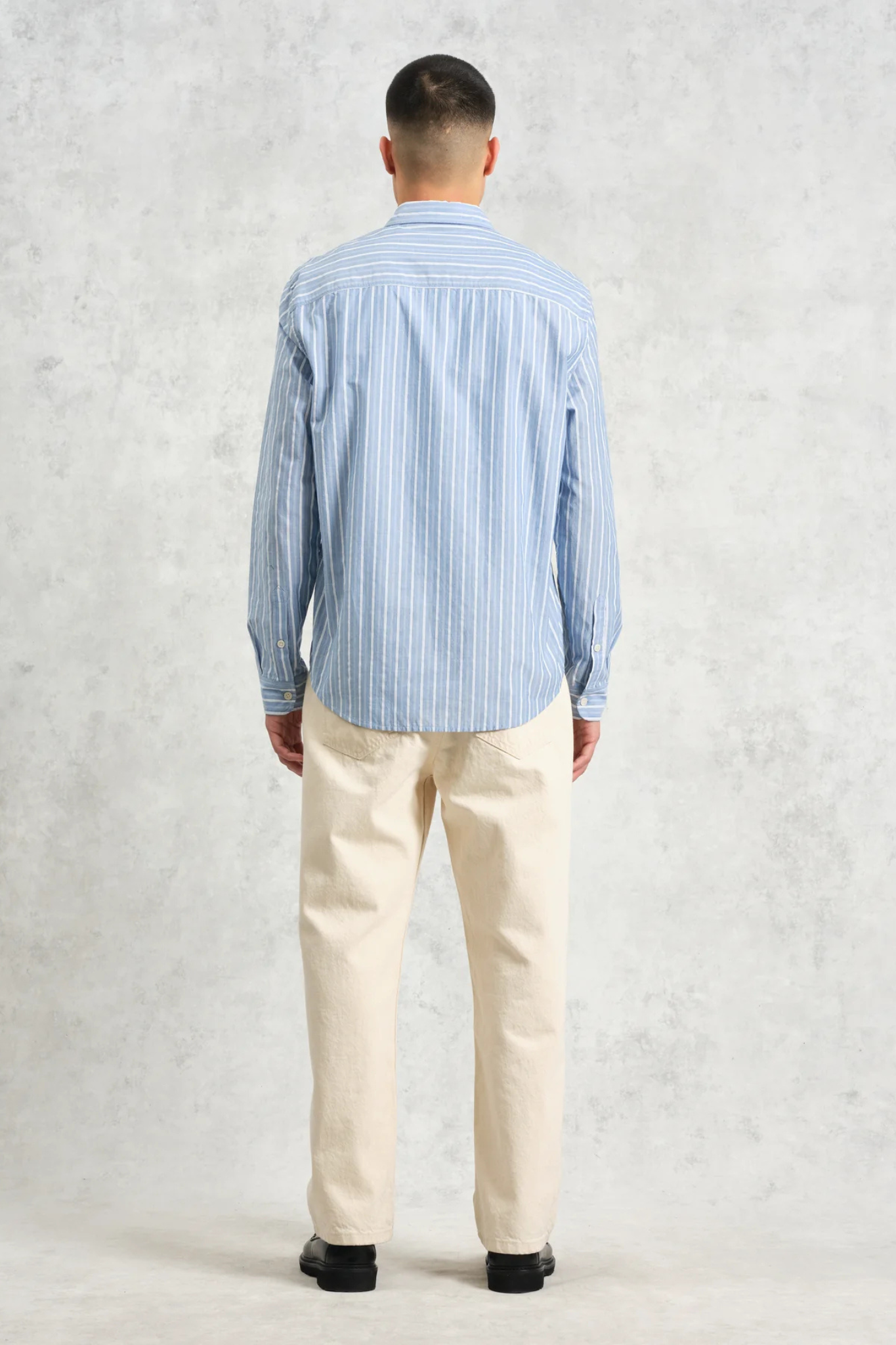 Model wearing the Wax London rove poplin stripe shirt in blue. Back view 