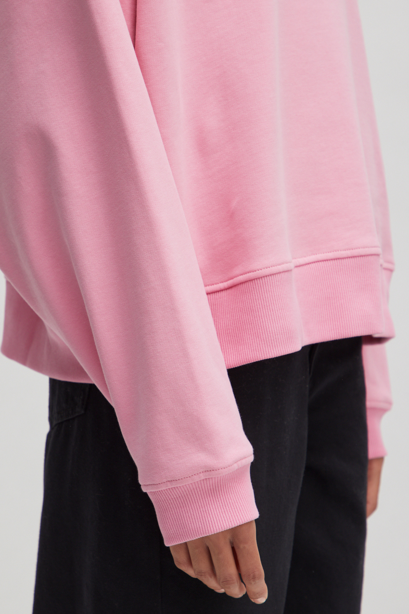 Model wearing the Edited Emielia sweater in pink. Close sleeve view