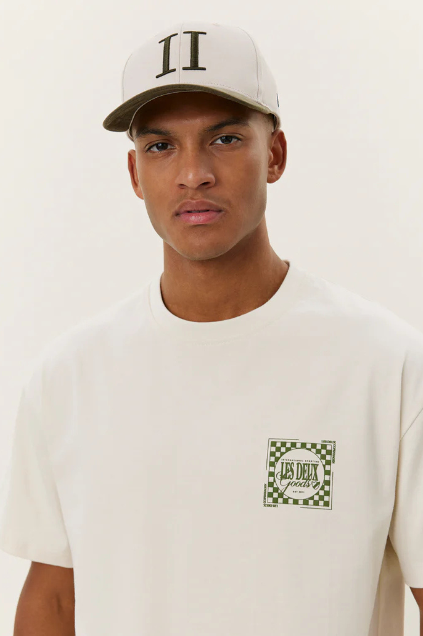 Model wearing the Les Deux goods t-shirt in ivory and green. Close front view