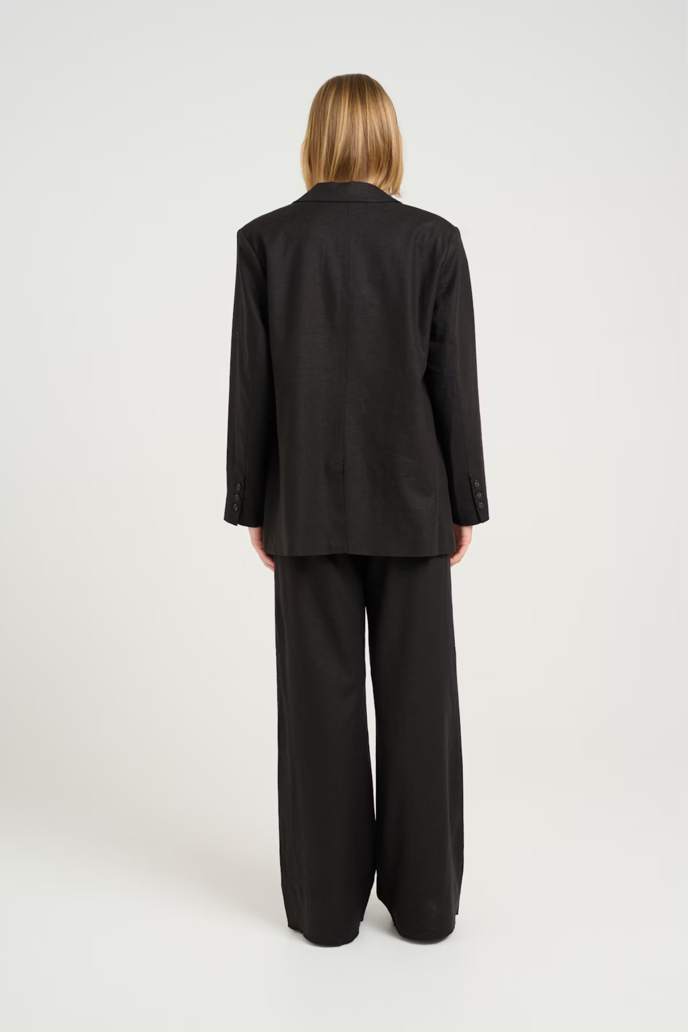 Model wearing the Gestuz elarah linen blazer in black. Back view