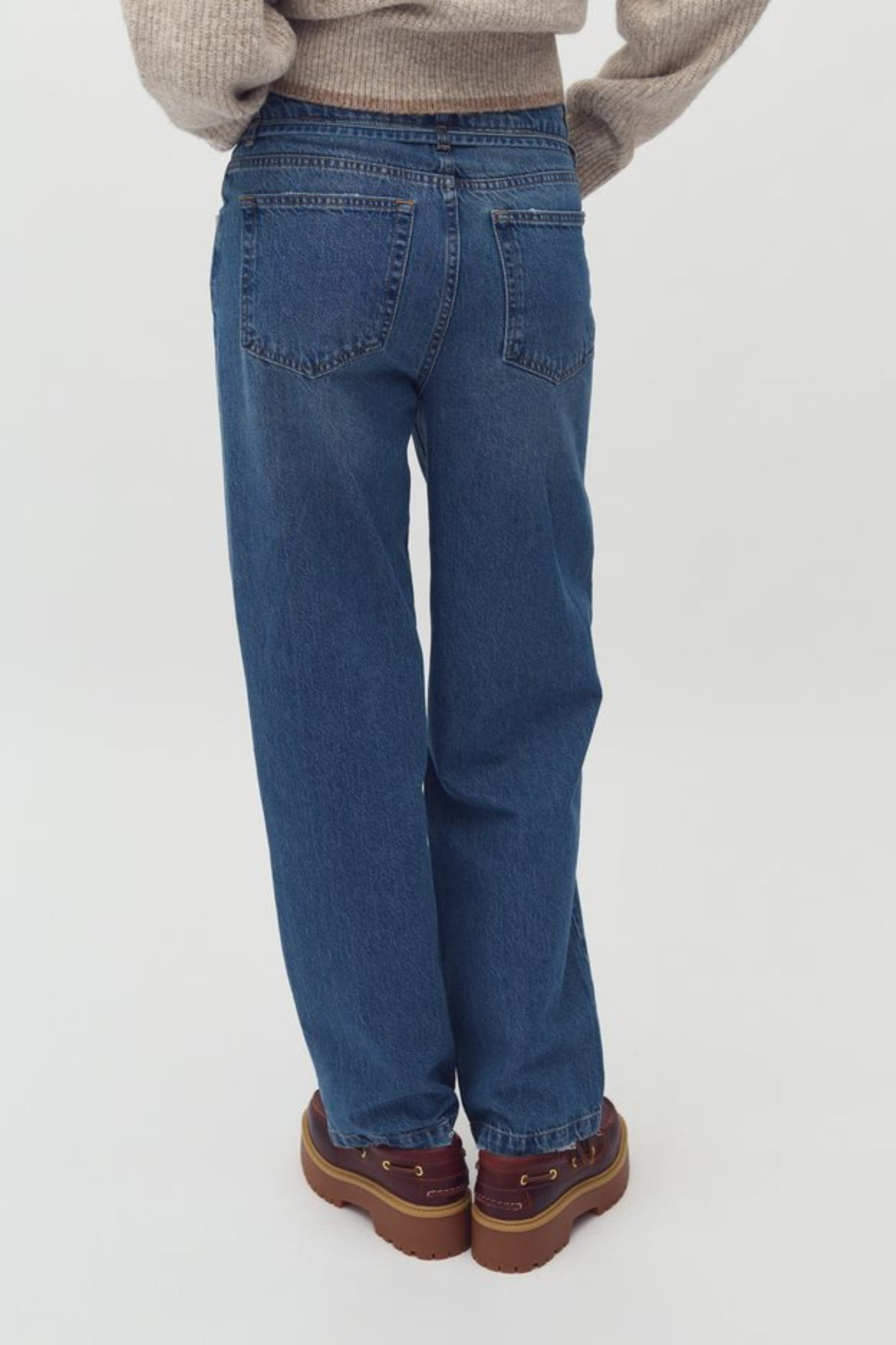 Model wearing the Mbym caria maya jeans in mid blue wash. Back view