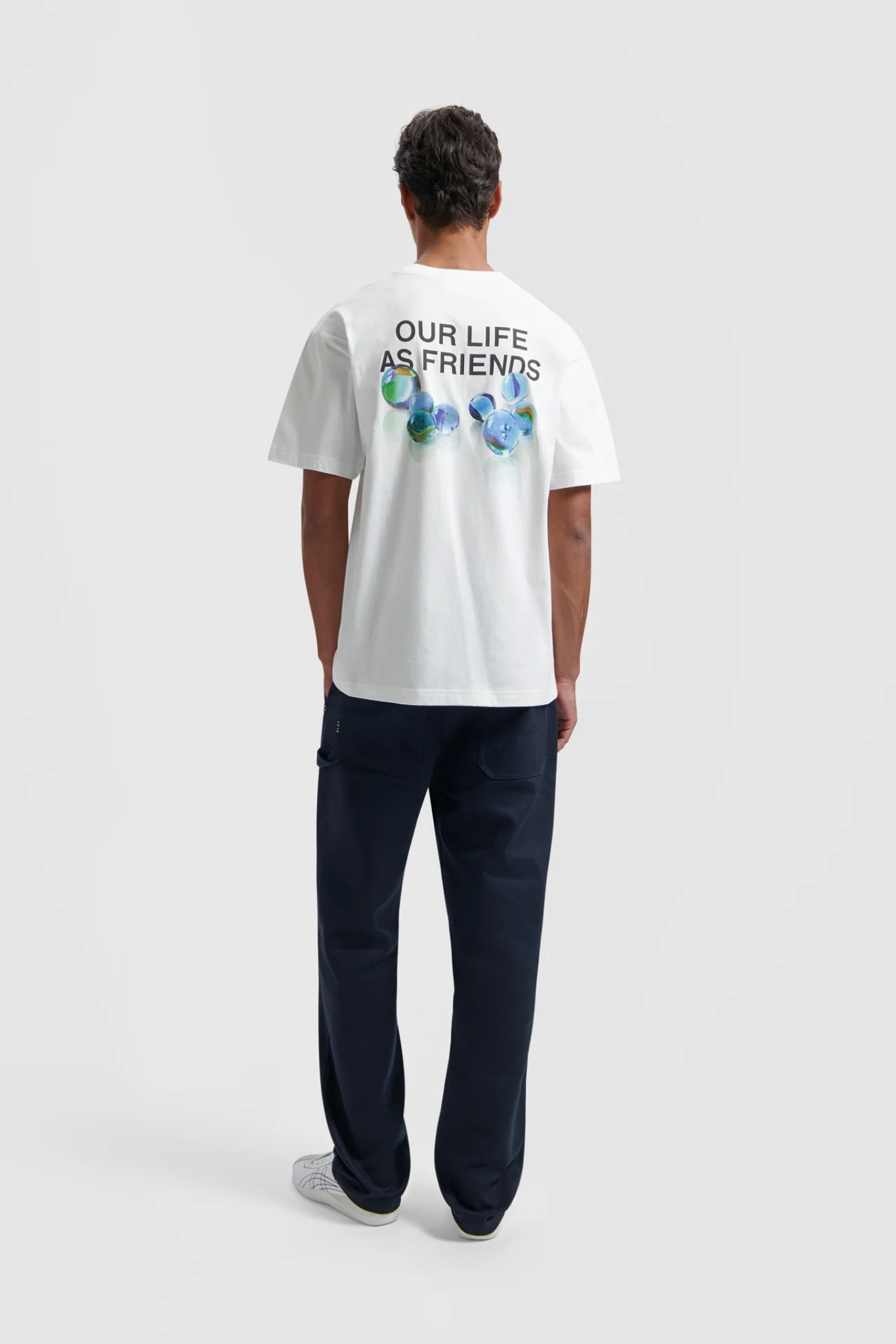 Model wearing the Olaf marbles t-shirt in white and graphic in blue. Back view