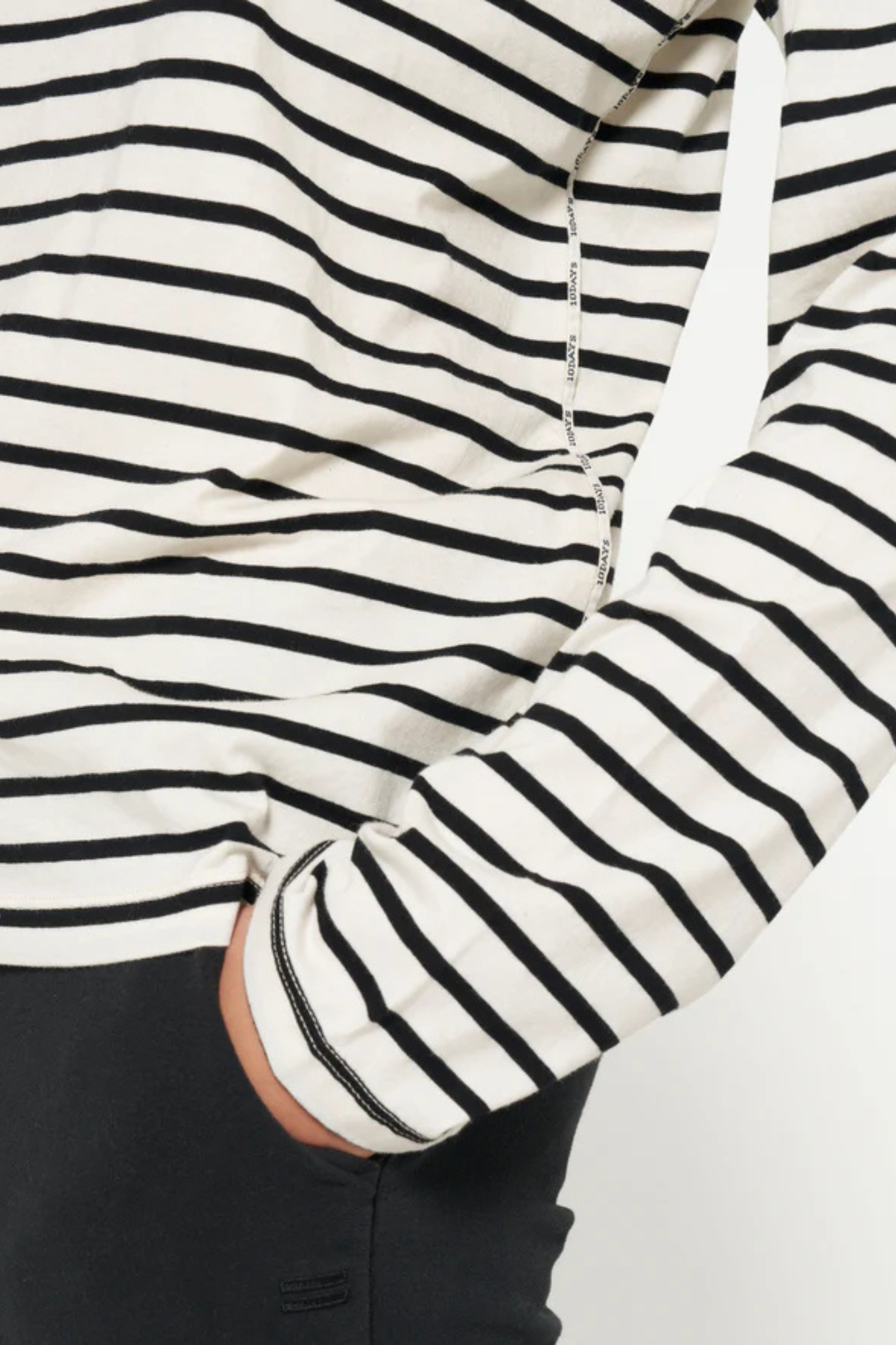 Model wearing the 10DAYS longsleeve in white and black stripe. Close sleeve view