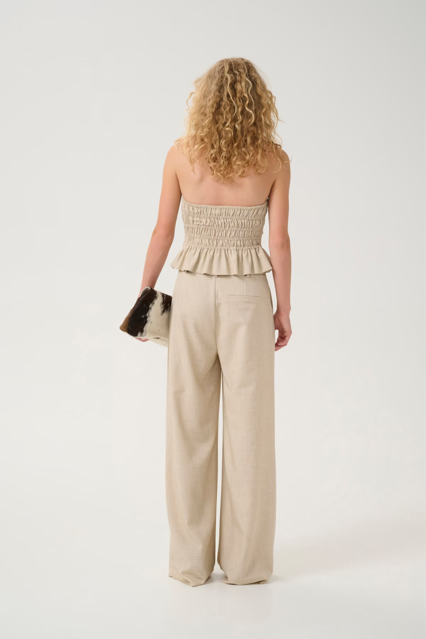 Model wearing the Gestuz decy pants in light sand melange. Back view